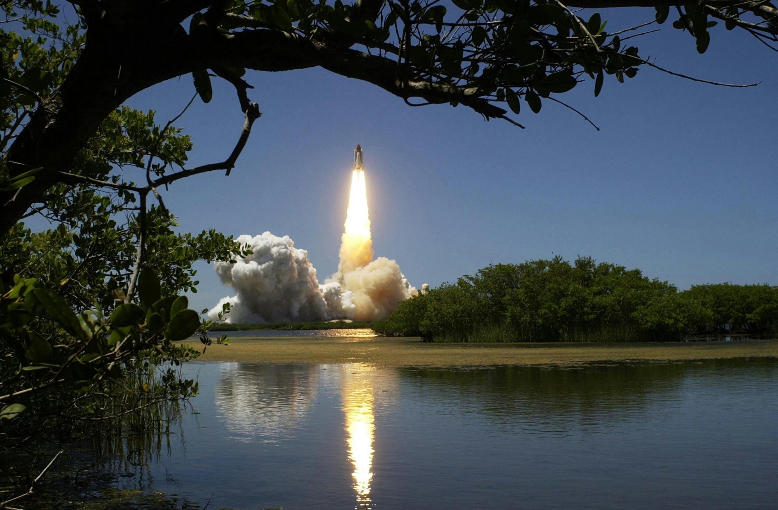 Lancering van een spaceshuttle gefotografeerd vanaf een moerasachtig gebied.