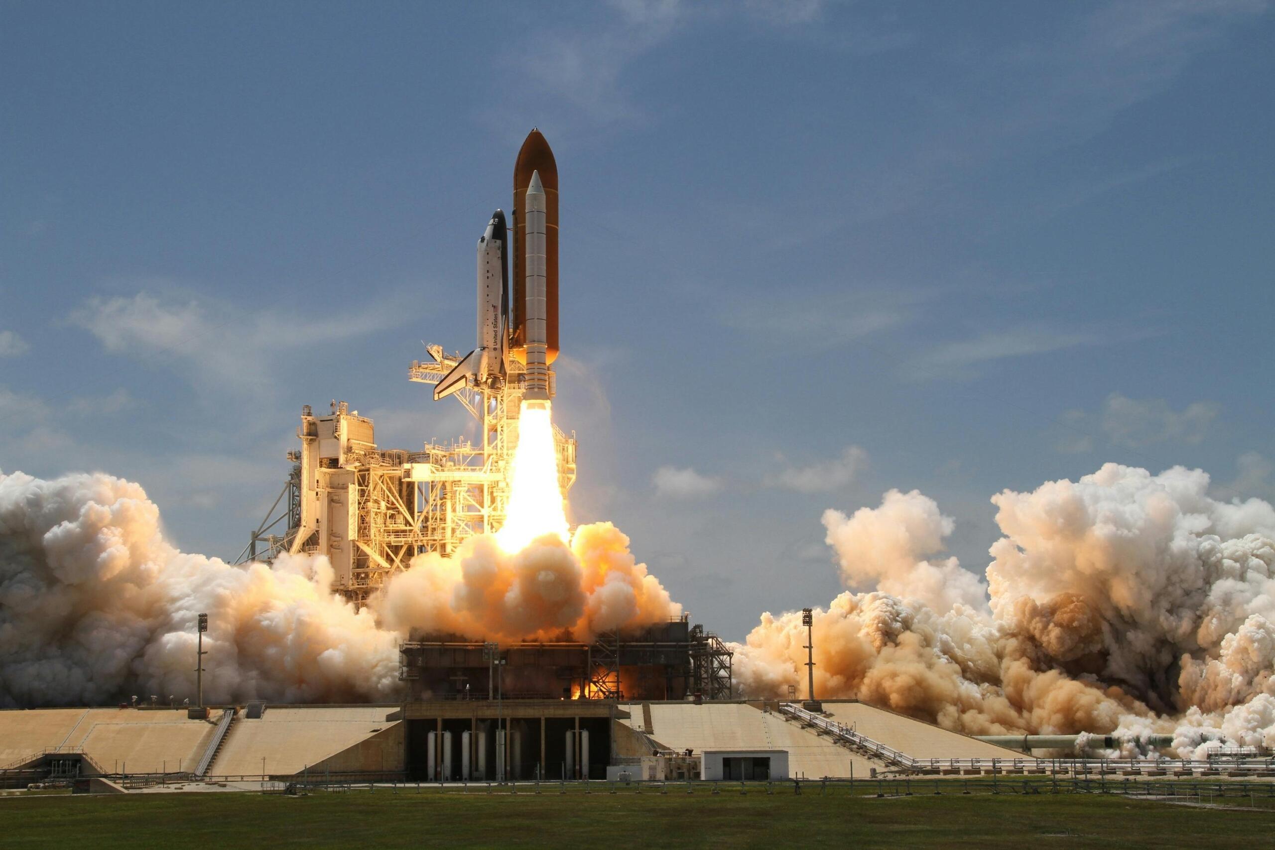 Een raketlancering vanaf een platform, met enorme rookwolken en heldere vlammen bij de opstijging.
