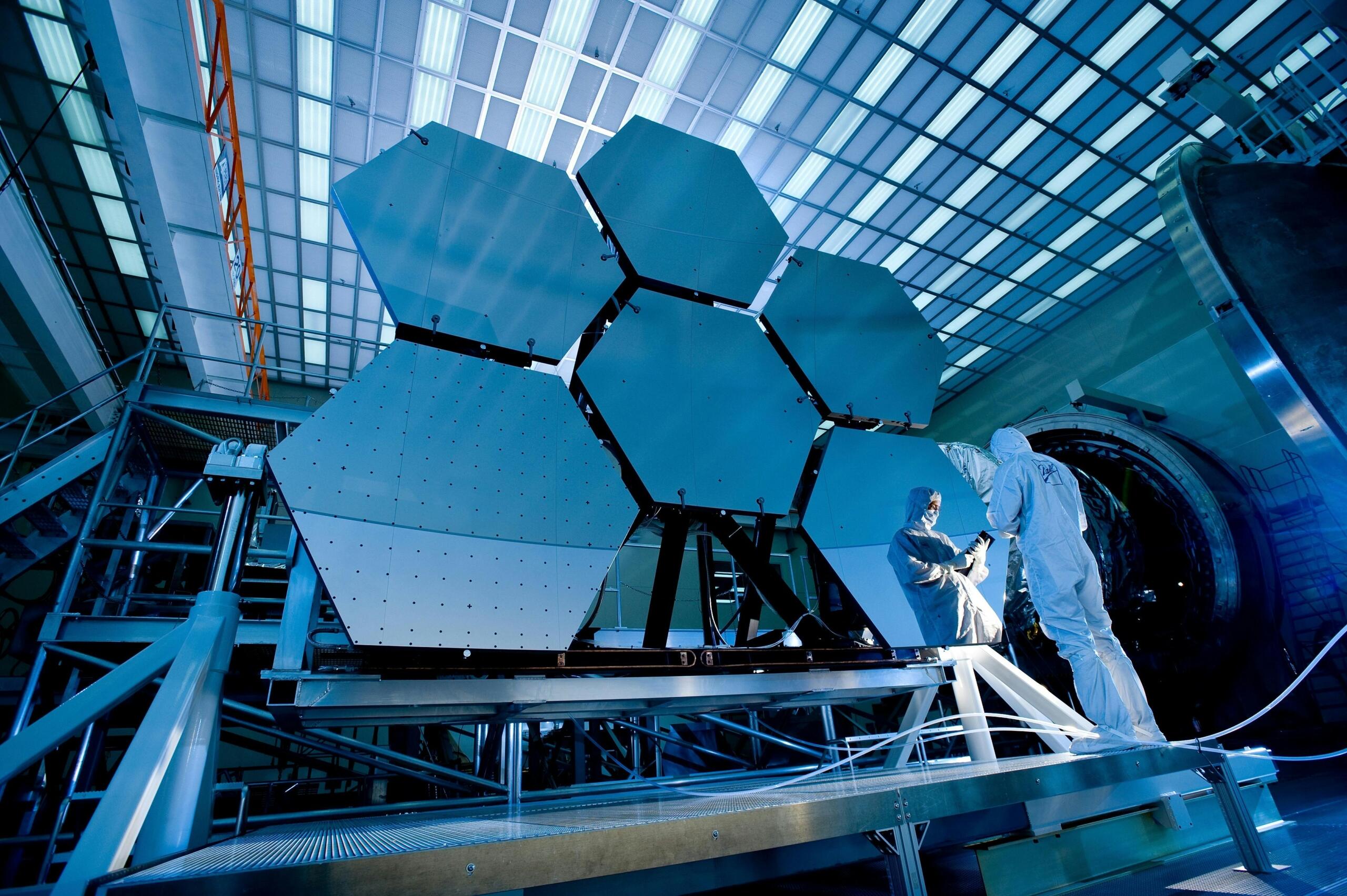 Wetenschappers werken in cleanroom aan een hexagonaal spiegelpaneel.