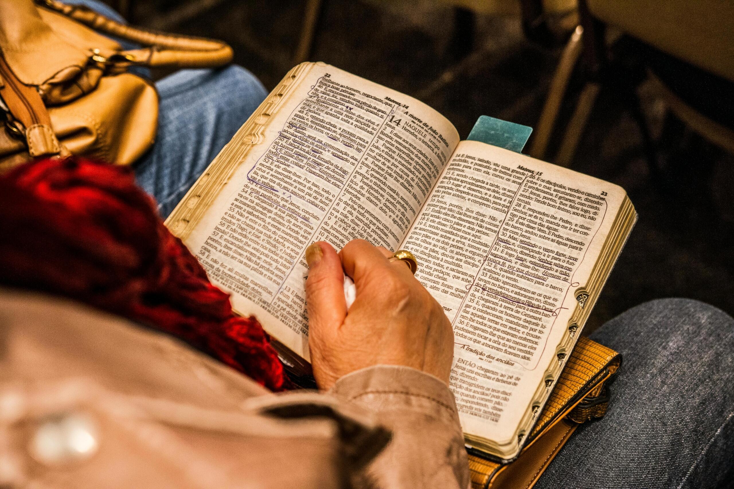 Een hand houdt een Hebreeuwse bijbel vast tijdens het lezen, een moment van studie of overdenking.
