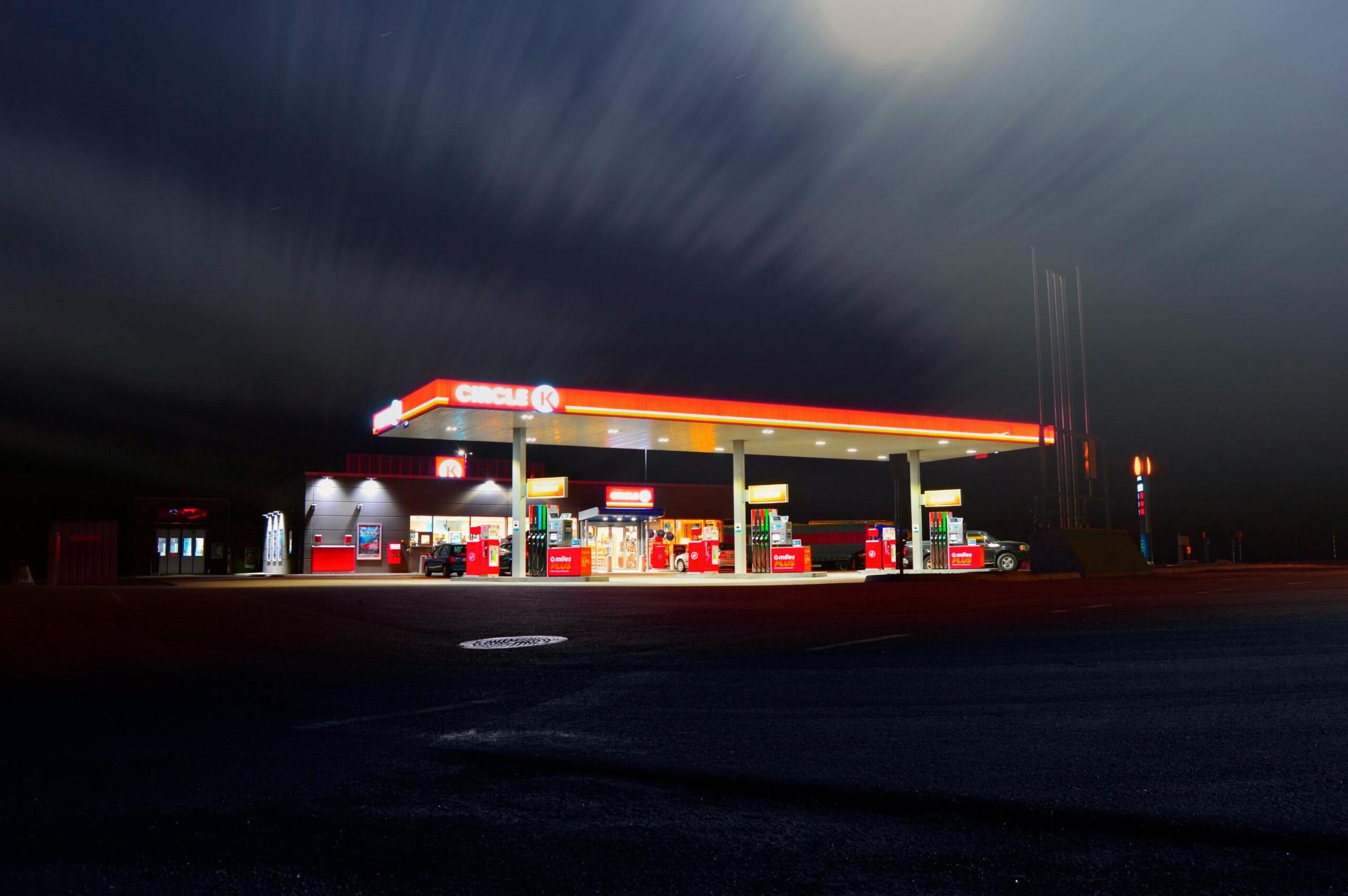 Een tankstation verlicht in de nacht.