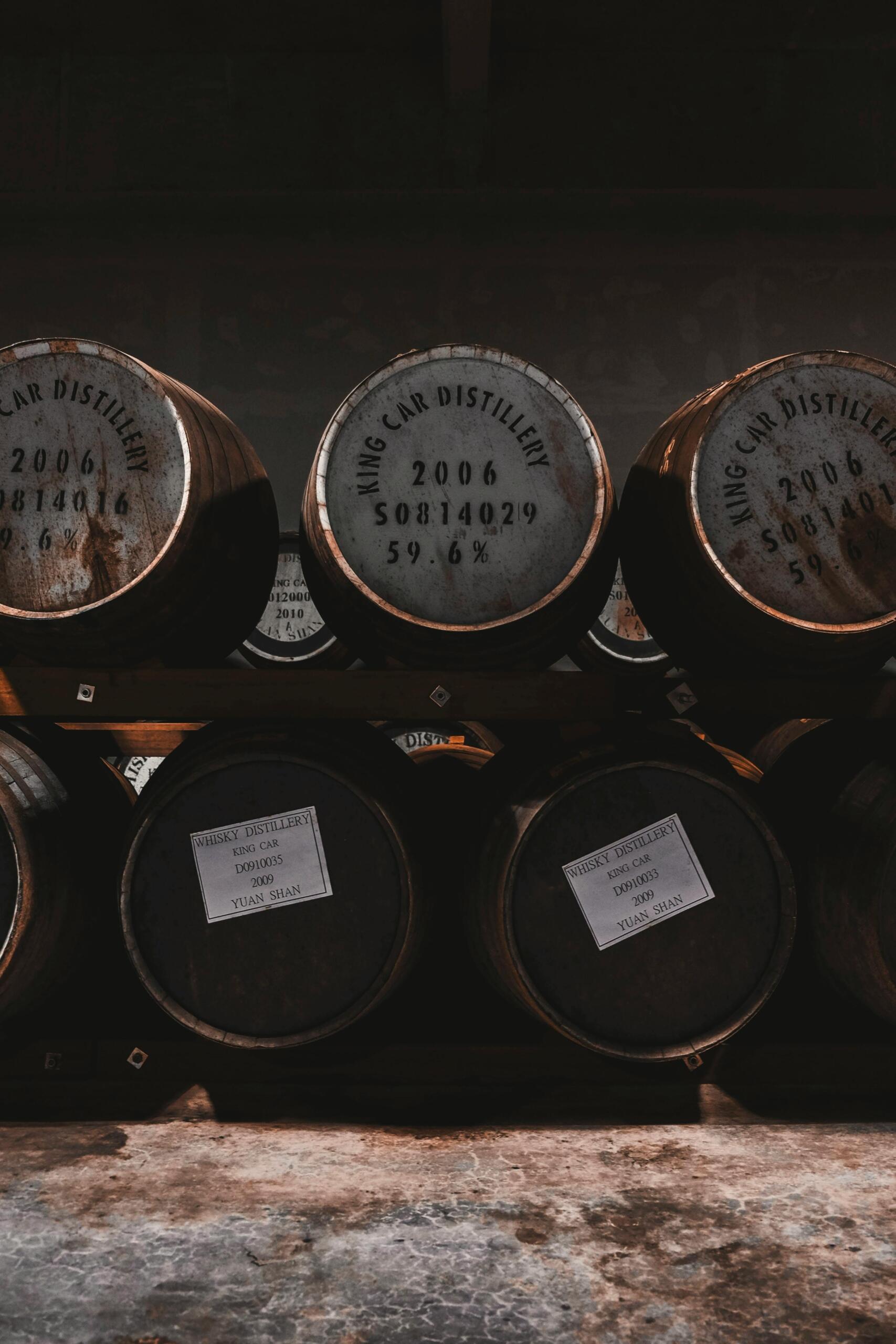 Houten whiskyvaten opgestapeld in een donkere opslagruimte.