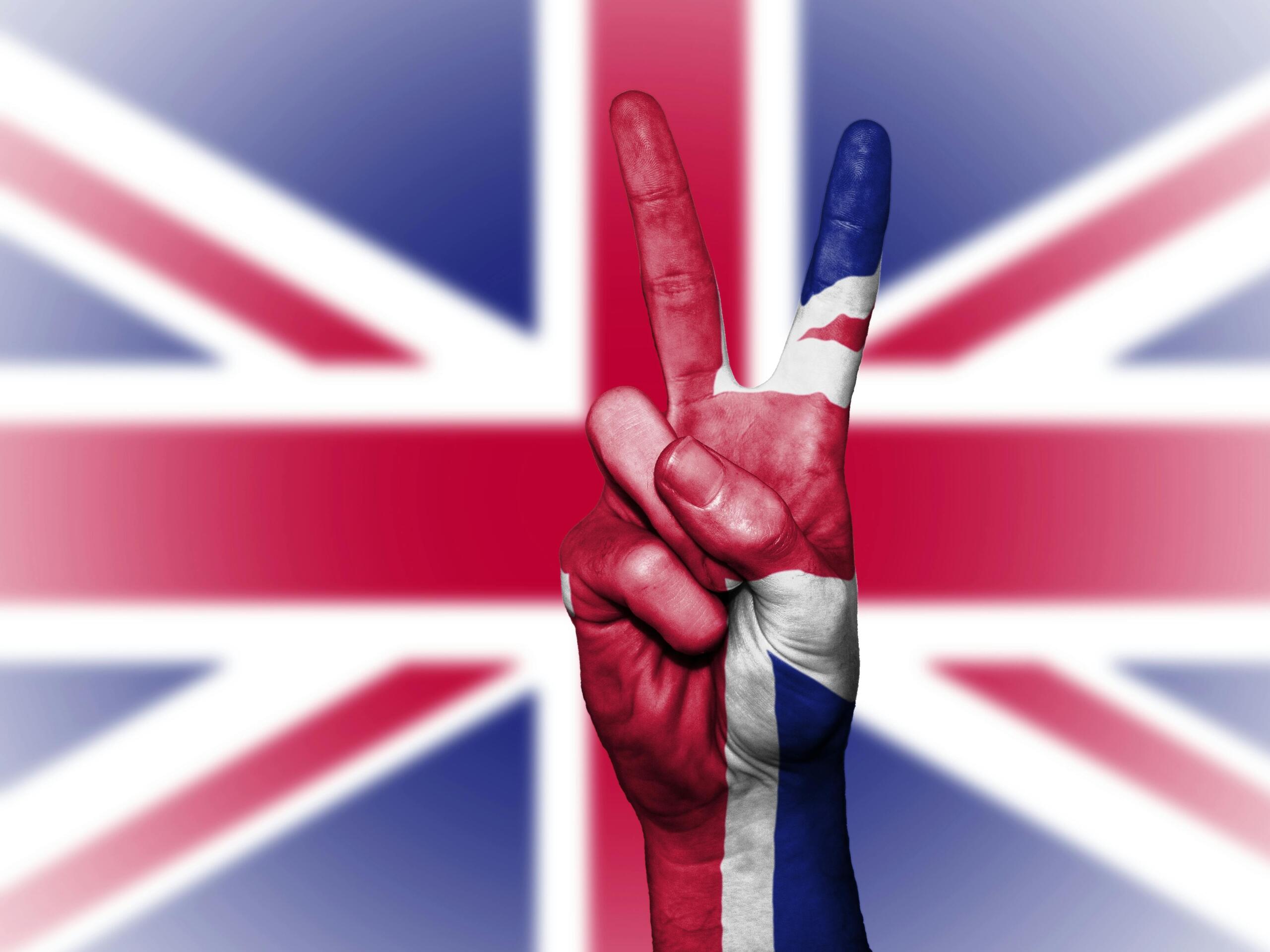 De Britse vlag, met een hand ervoor die twee vingers opsteekt.