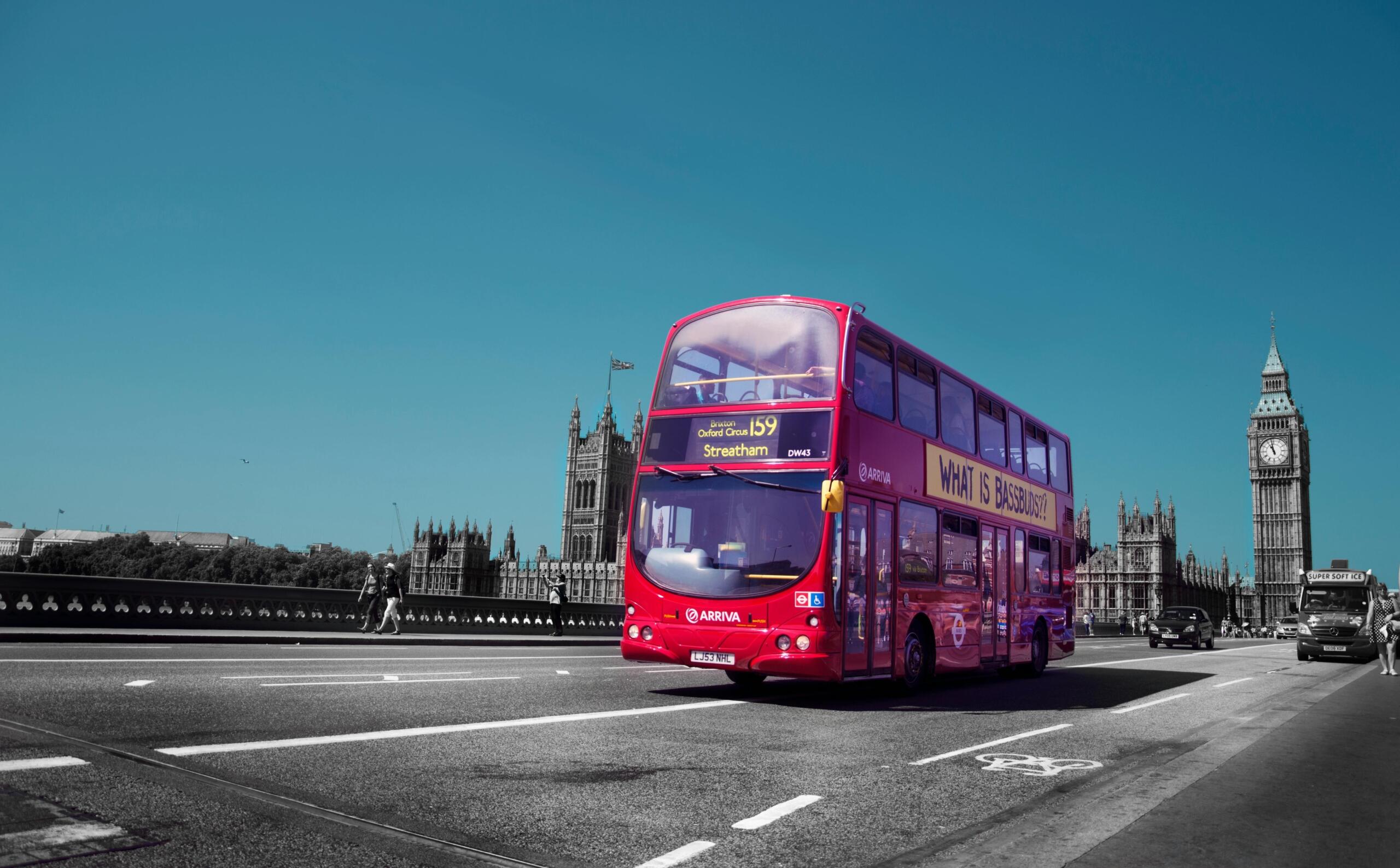 Een rode dubbeldekker rijdt over Westminster Bridge met Big Ben op de achtergrond.