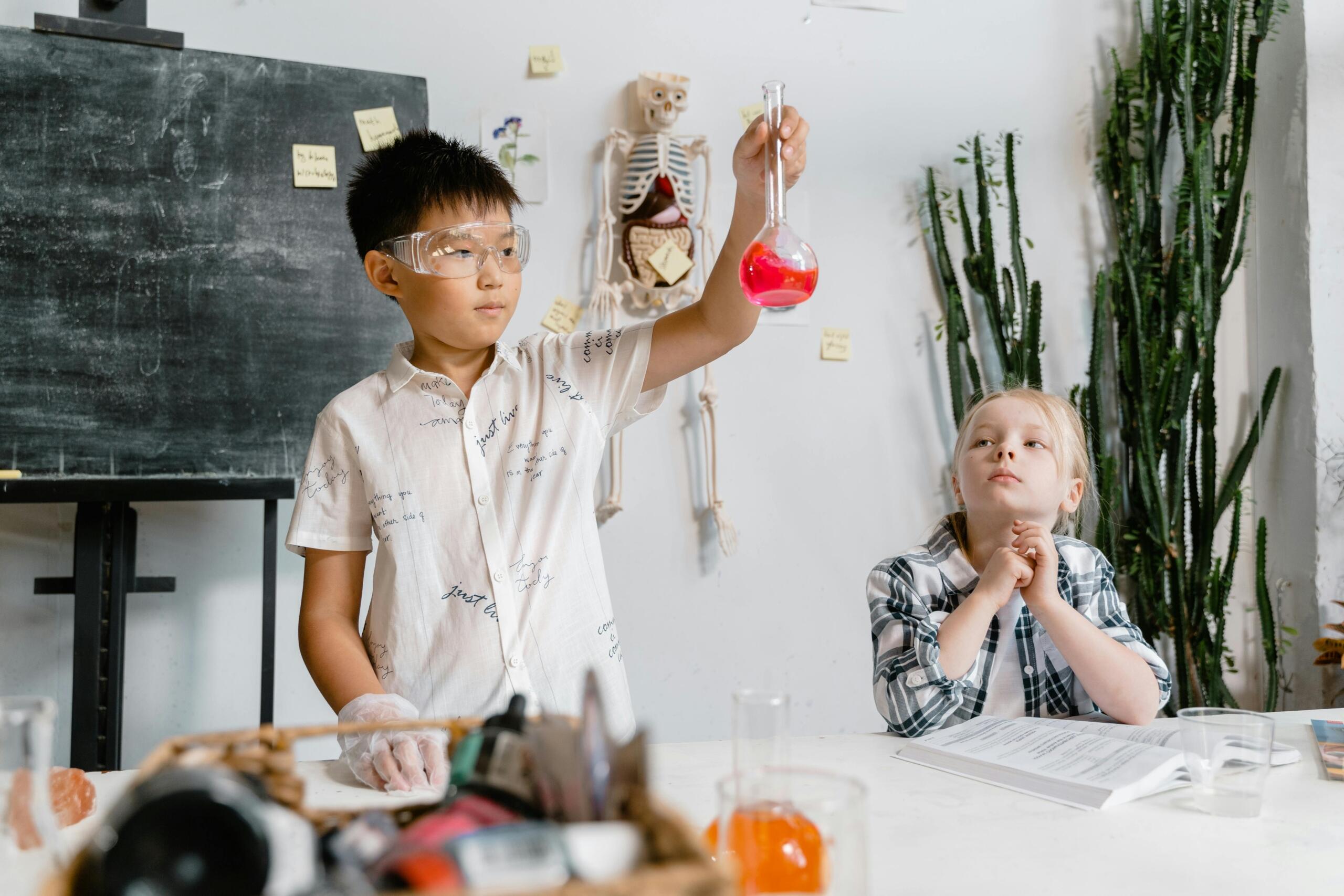 Twee kinderen in een klas, één houdt een fles met roze vloeistof omhoog.