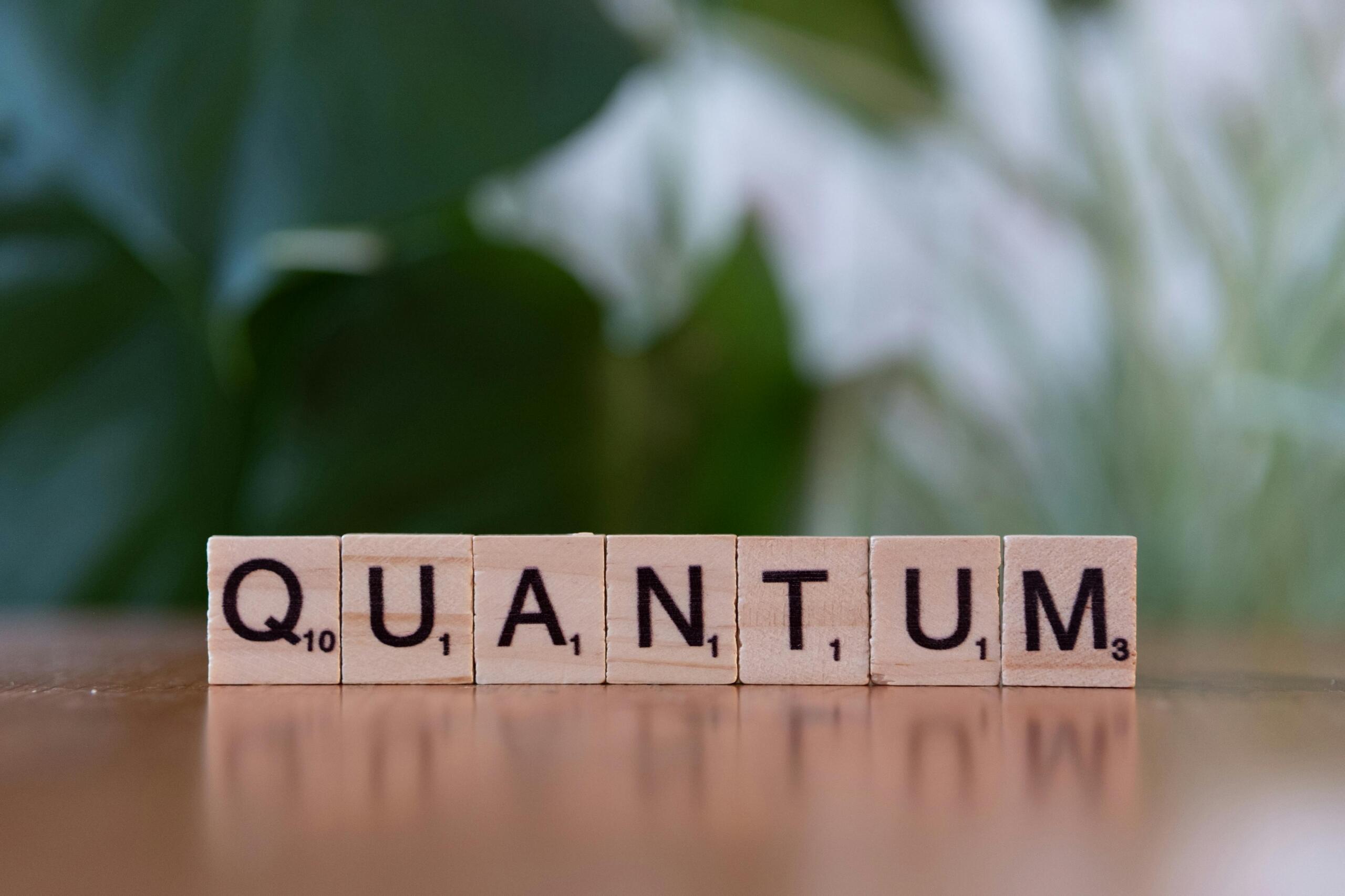 Scrabbleletters die samen het woord “QUANTUM” vormen.
