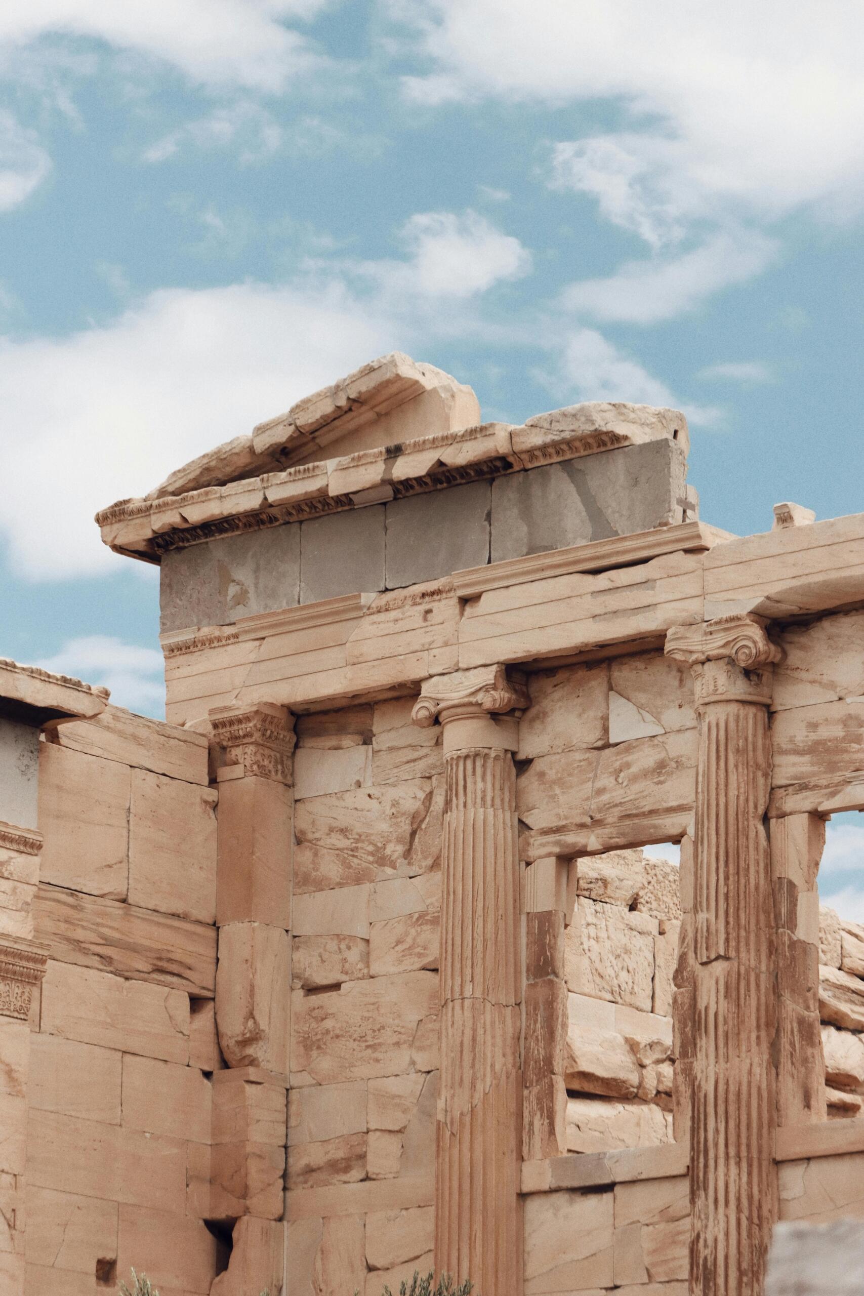 Een oude ruïne met zuilen en fragmenten van een Griekse tempel tegen een heldere hemel.