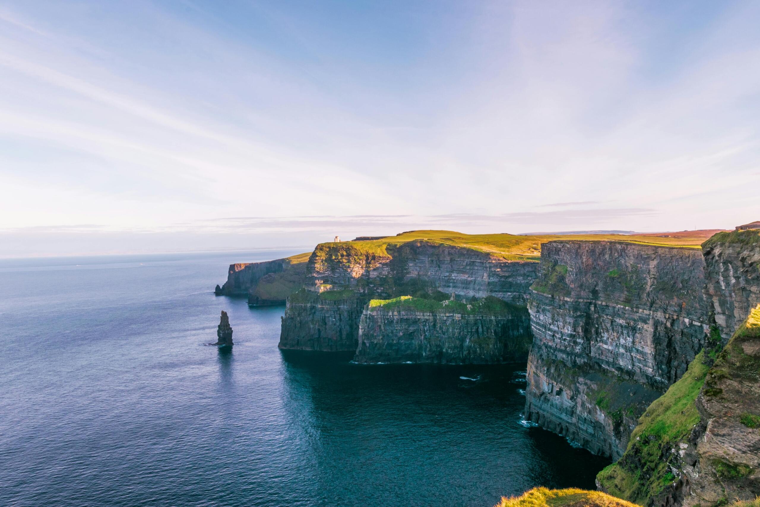 Uitzicht op de Cliffs of Moher aan de Atlantische kust van Ierland met hoge kliffen en kalm water eronder.