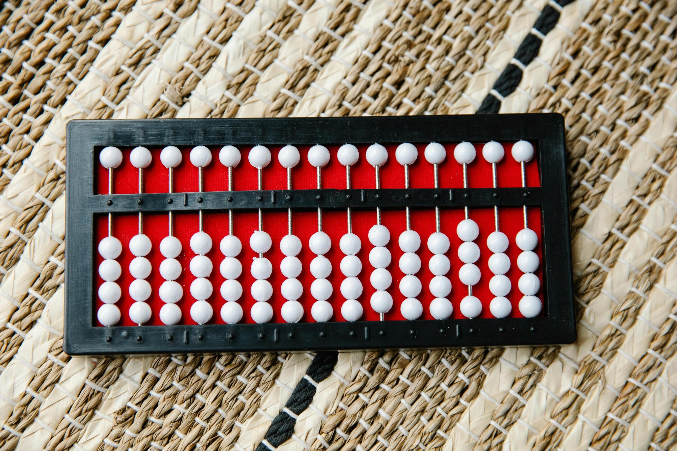 Traditionele Chinese abacus met witte kralen op een rode achtergrond en gevlochten ondergrond.