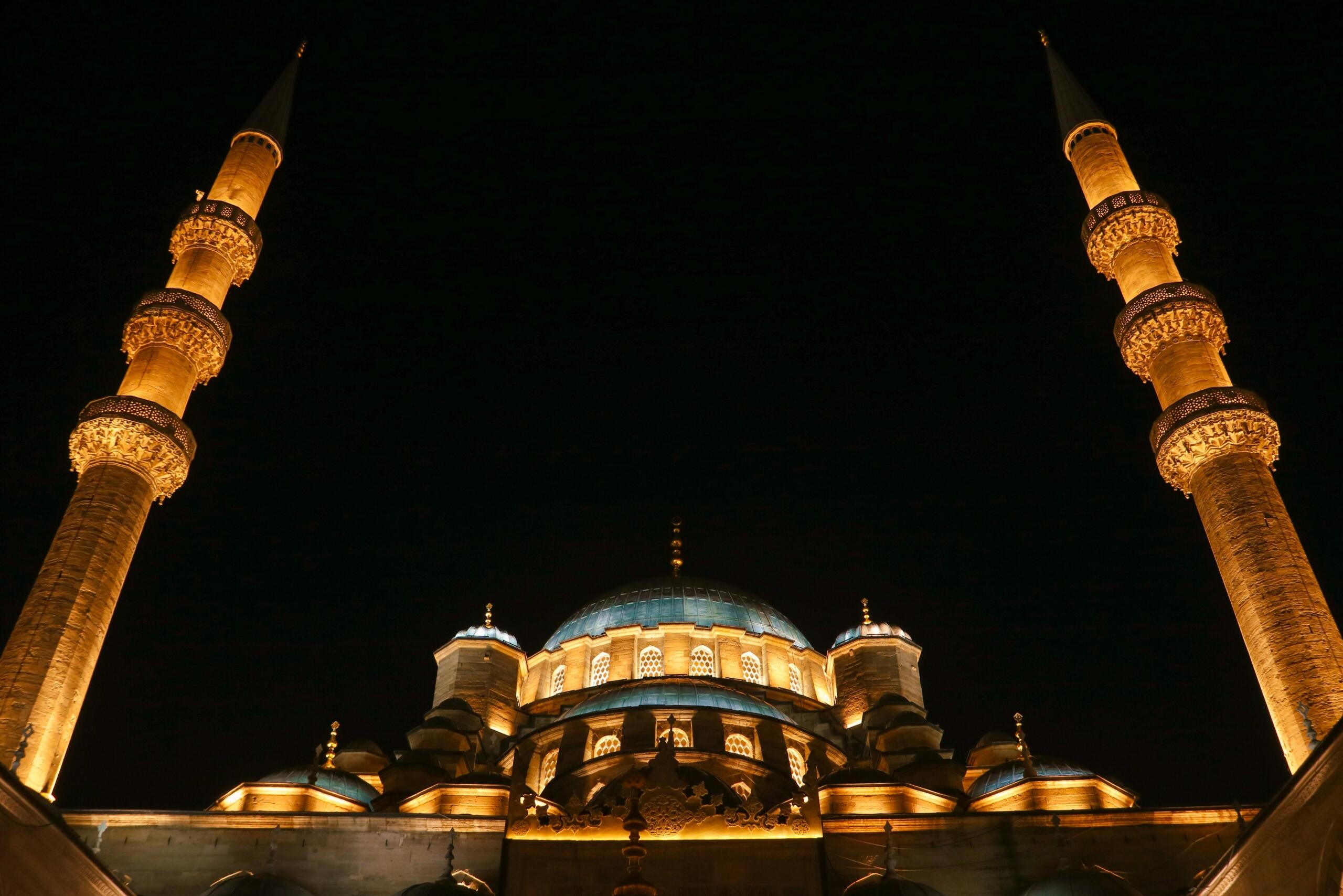 De verlichte Blauwe Moskee in Istanboel rijst ’s nachts op, met minaretten en koepels die oplichten tegen de donkere hemel.