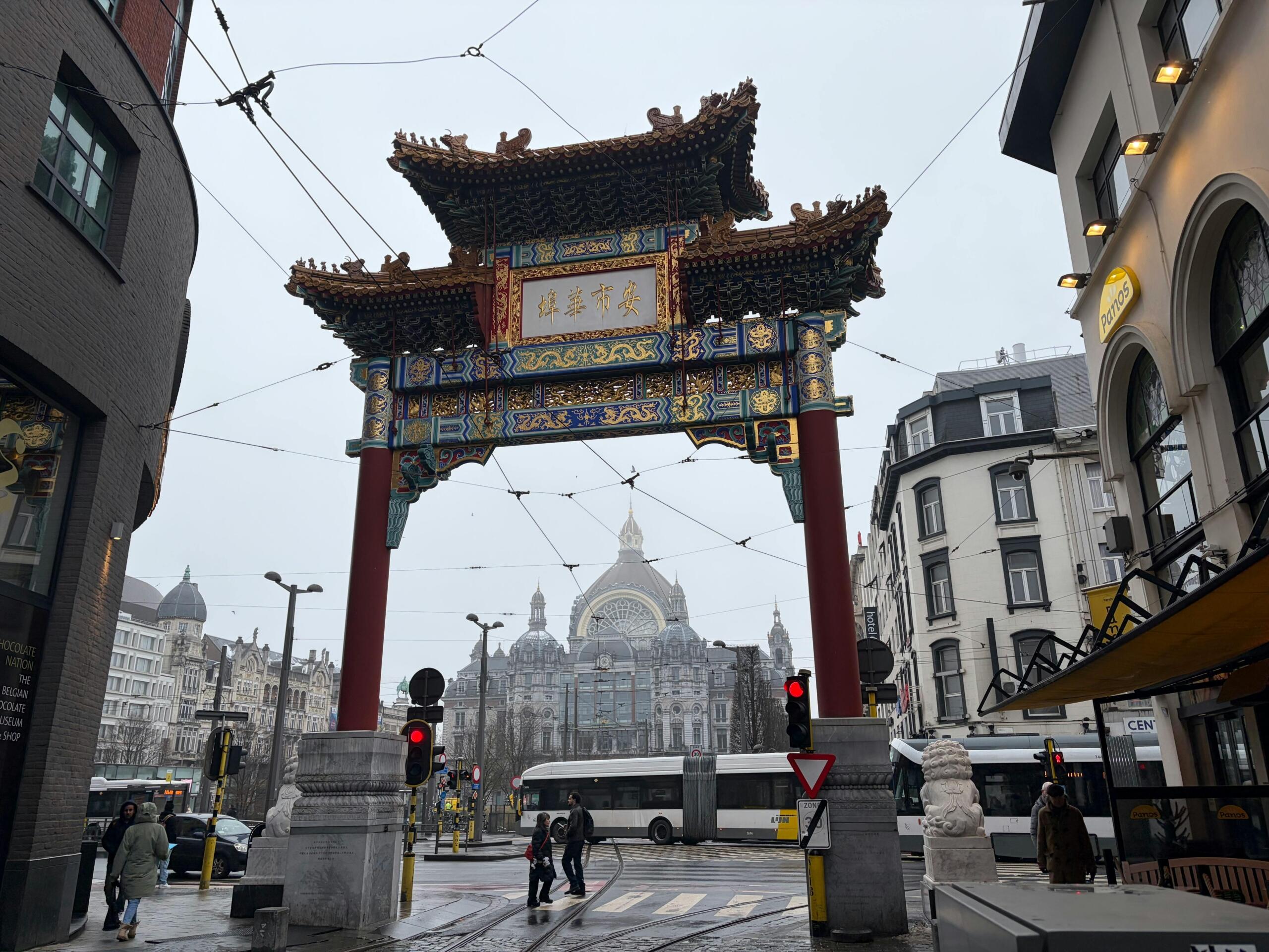 Traditionele Chinese poort in een stedelijke omgeving met verkeer en voetgangers.
