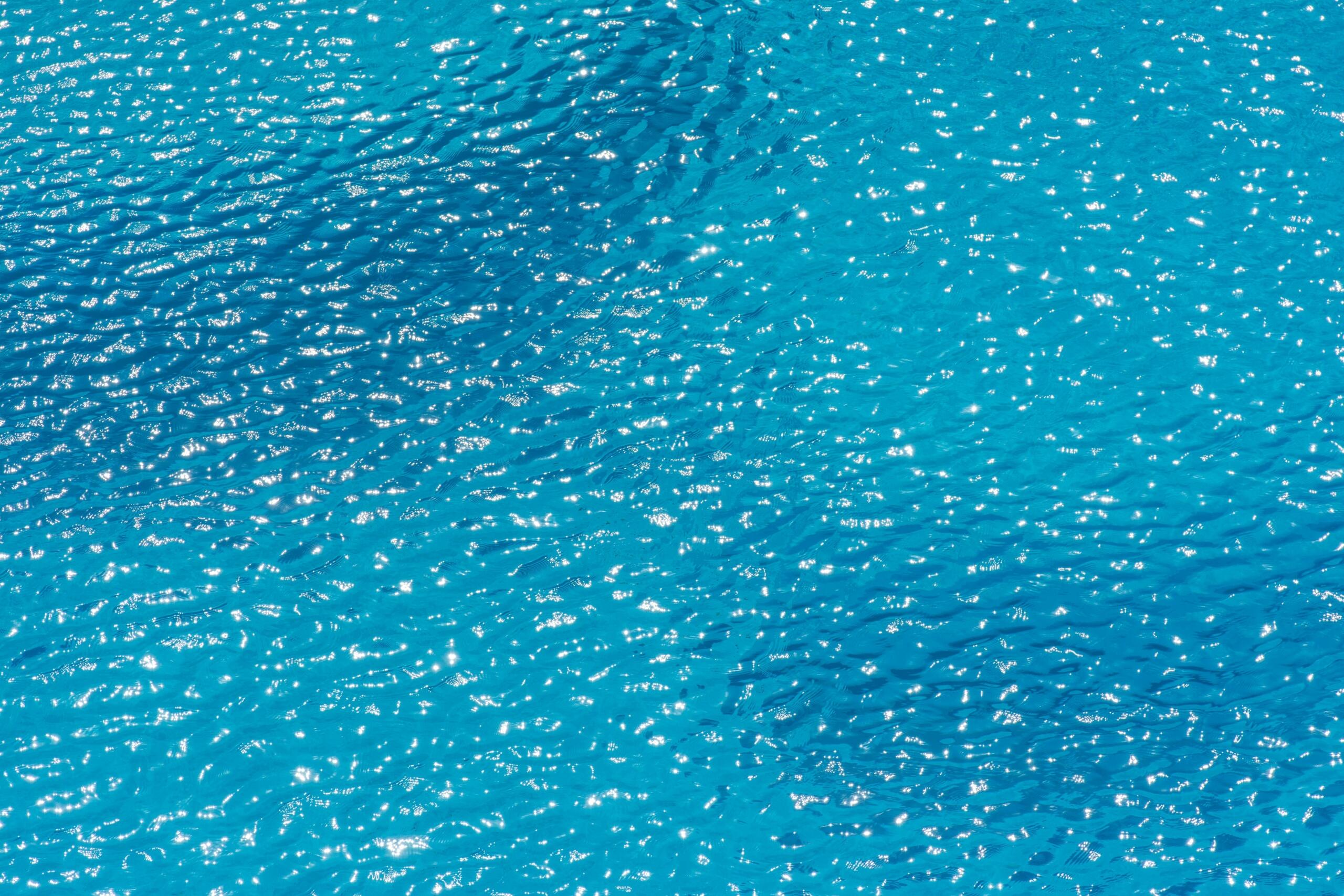 Uitgestrekt turquoise wateroppervlak met fonkelende rimpels onder zacht zonlicht.