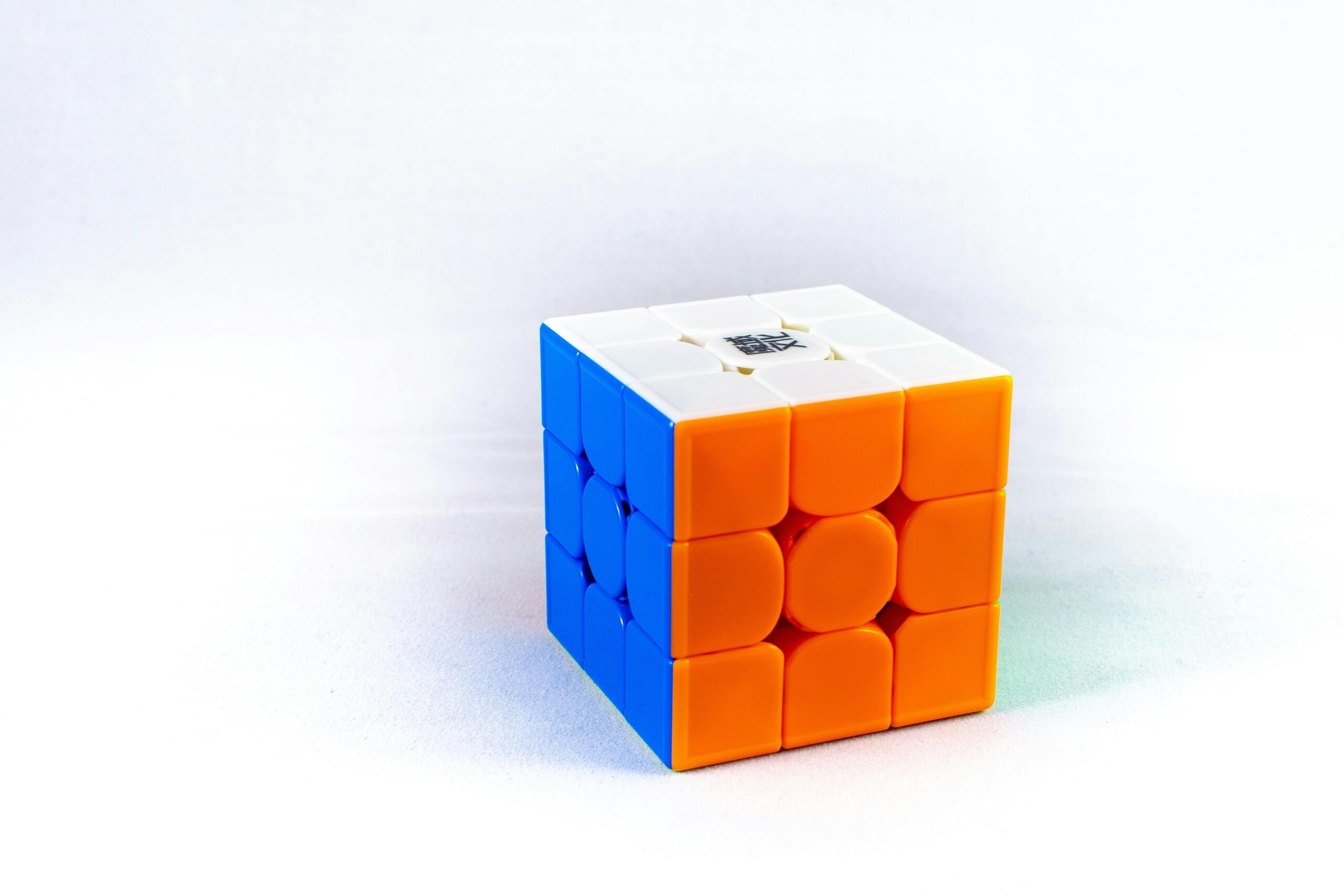 Felgekleurde 3x3 Rubik’s kubus hangt tegen een witte achtergrond.
