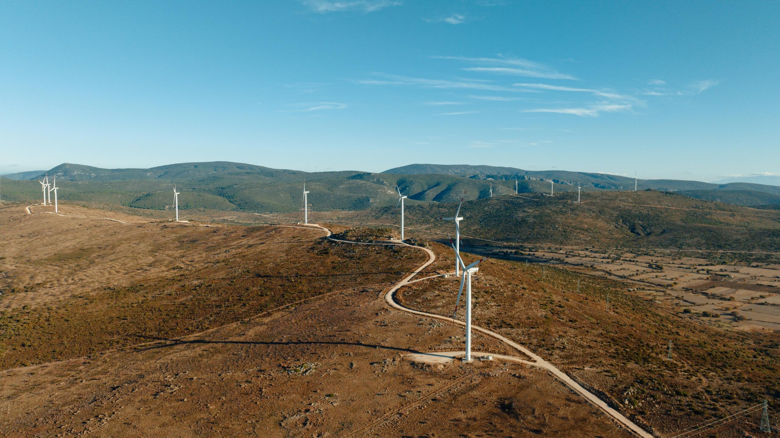Luchtfoto van meerdere windturbines op een heuvel in een open landschap.