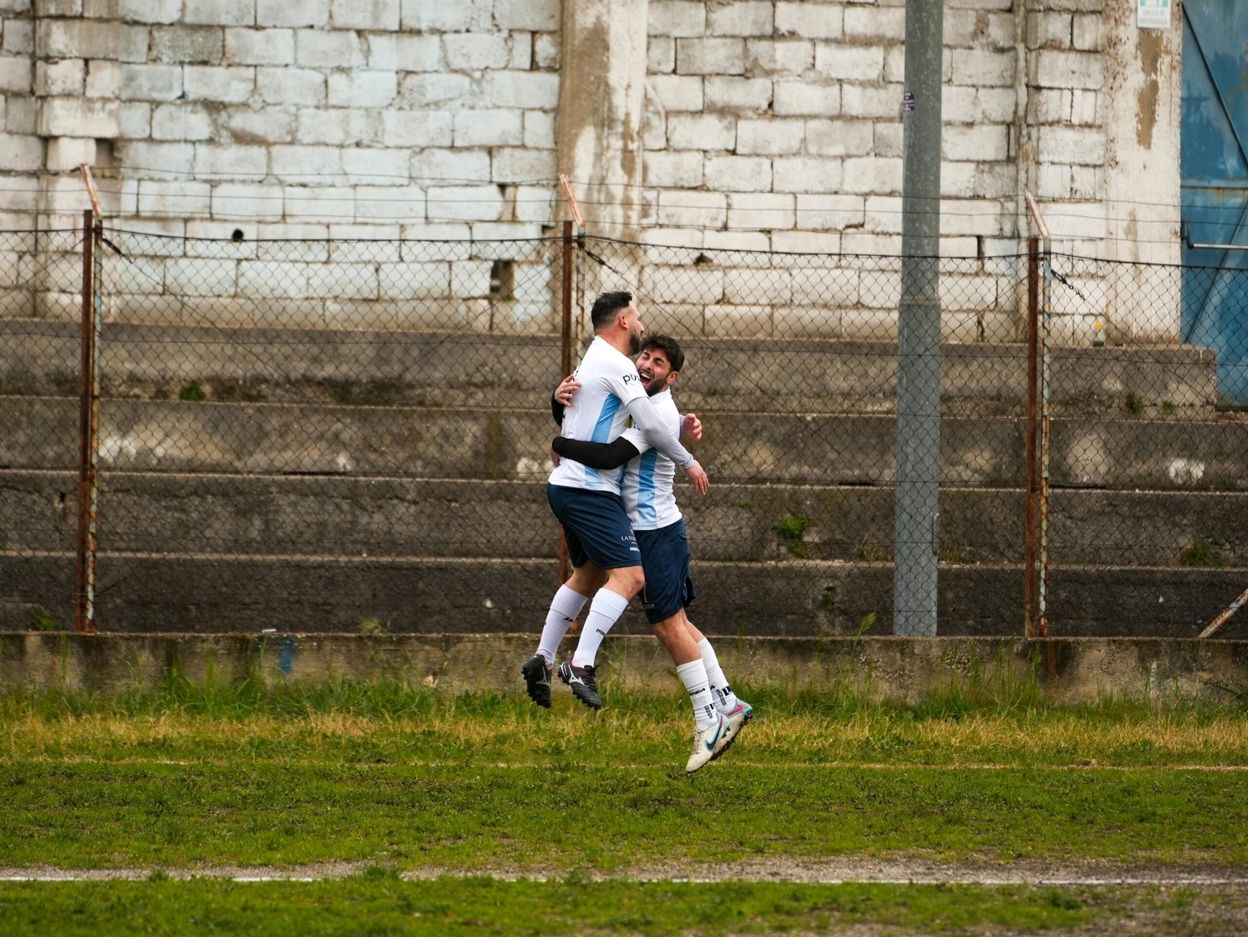 Twee voetballers vieren een doelpunt op het veld.