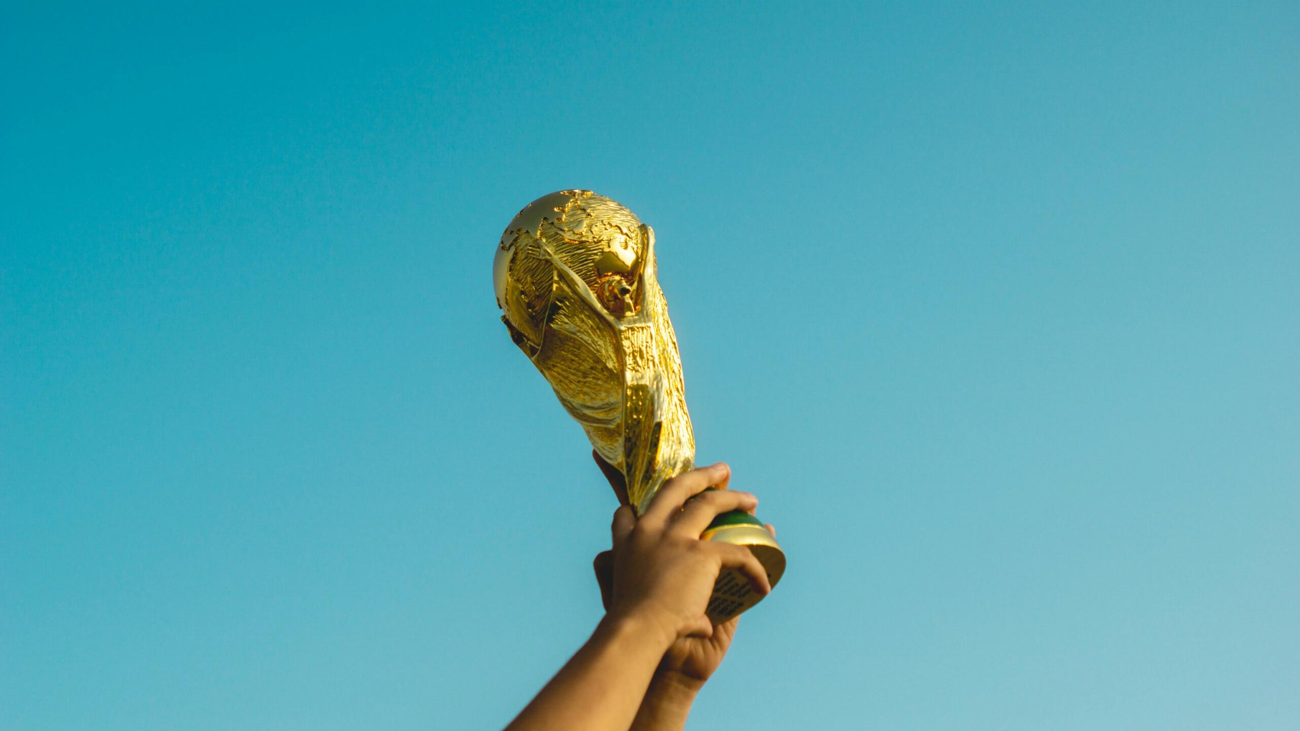 Een persoon houdt een gouden trofee omhoog.