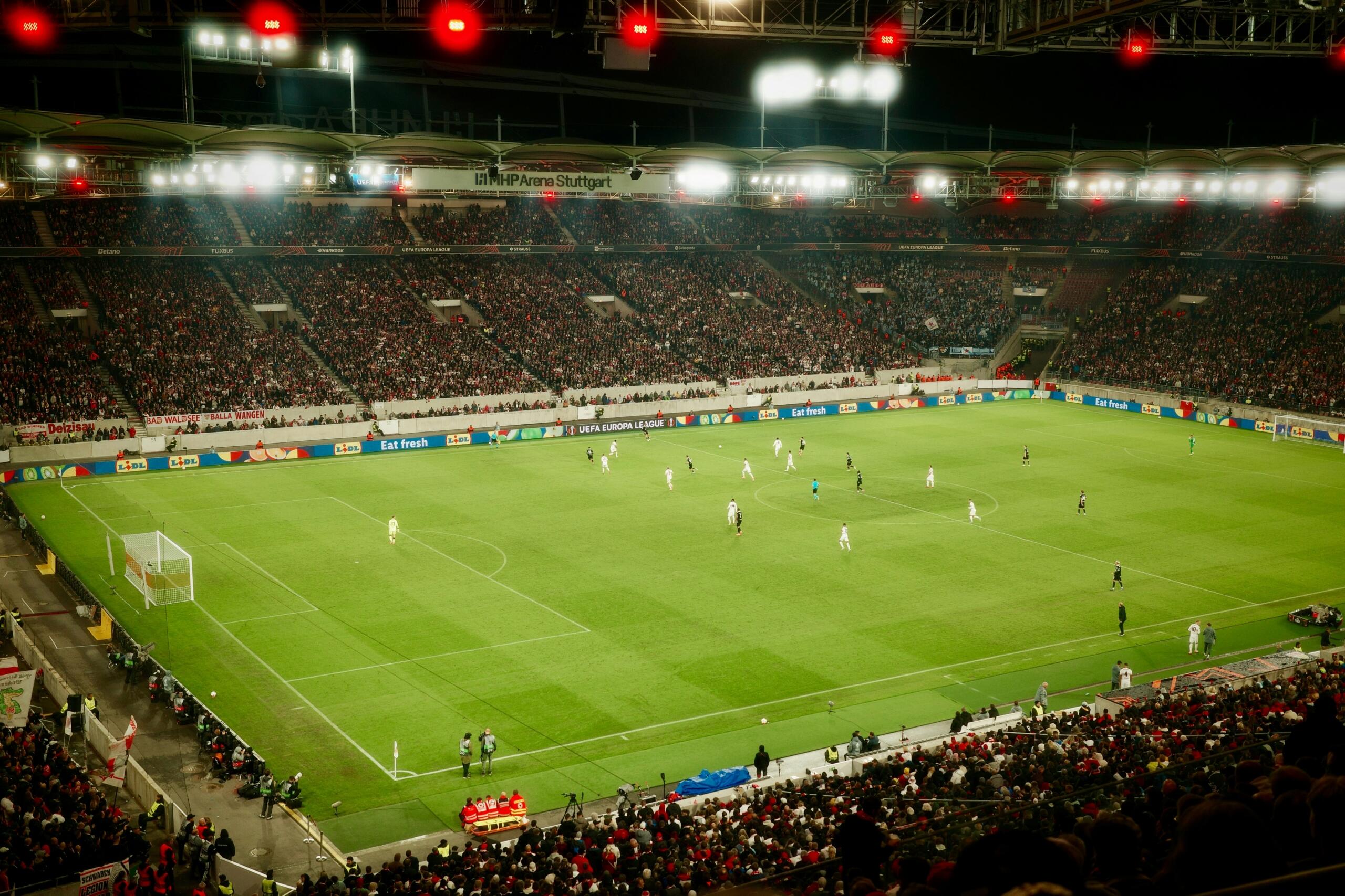 Een voetbalwedstrijd wordt gespeeld in een vol stadion bij nacht.
