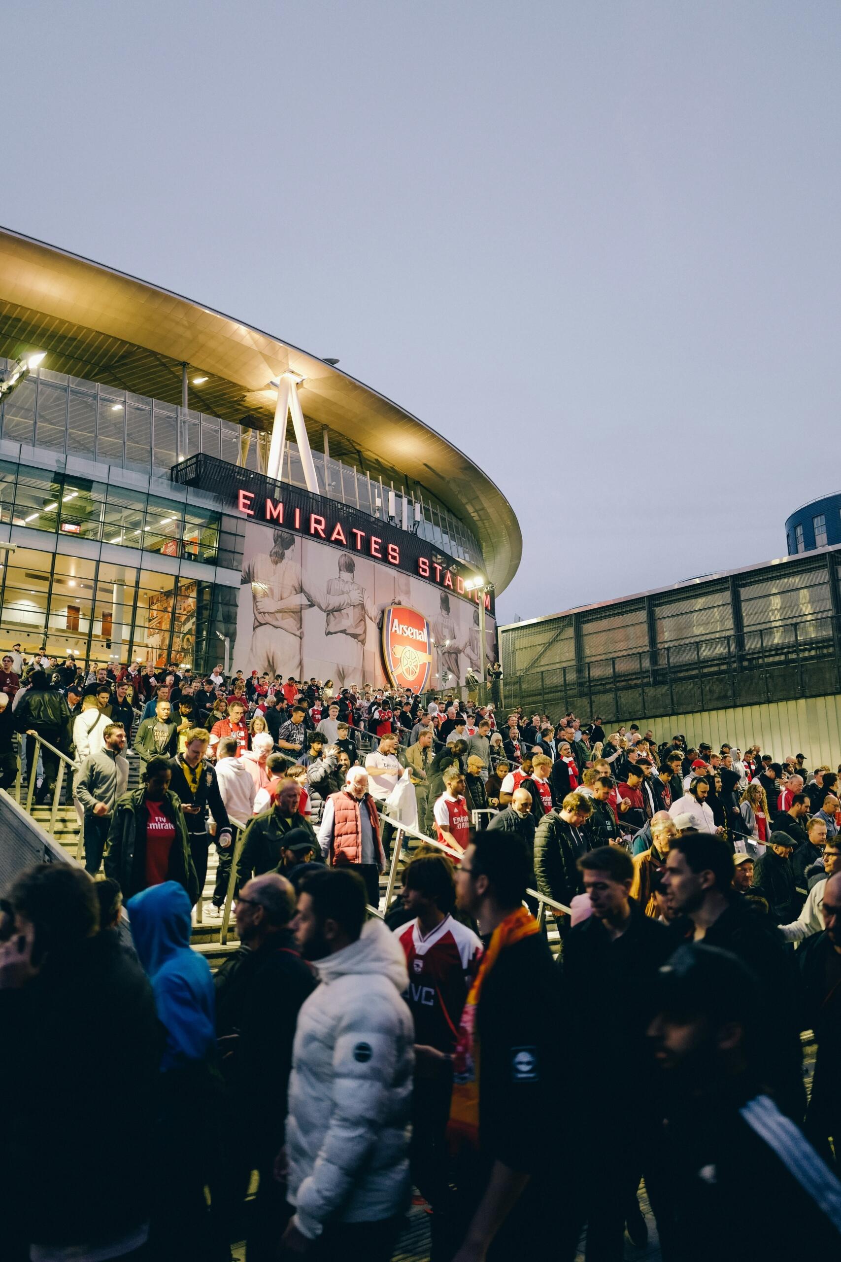 Een groep mensen staat buiten een stadion.