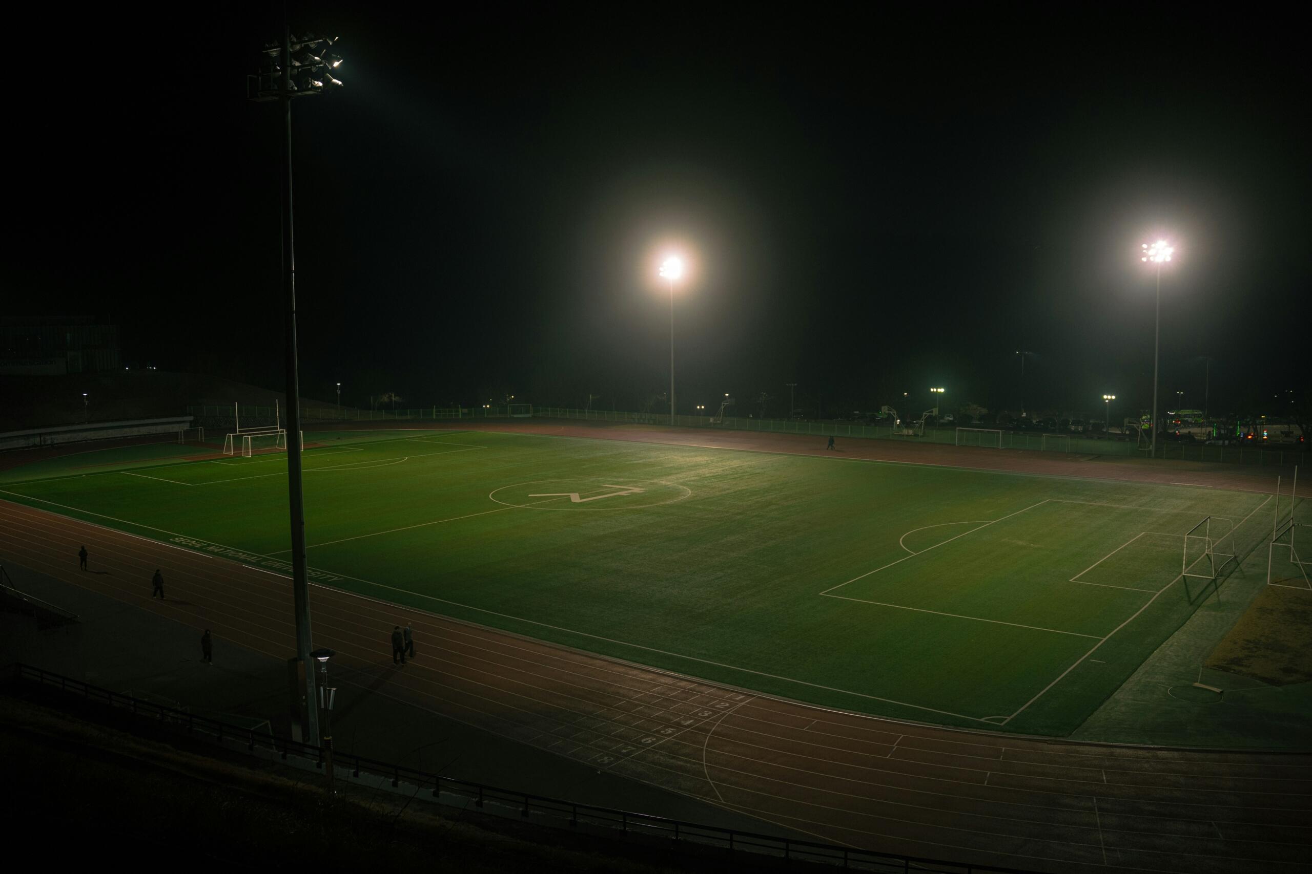 Een verlicht voetbalveld is te zien in het donker.