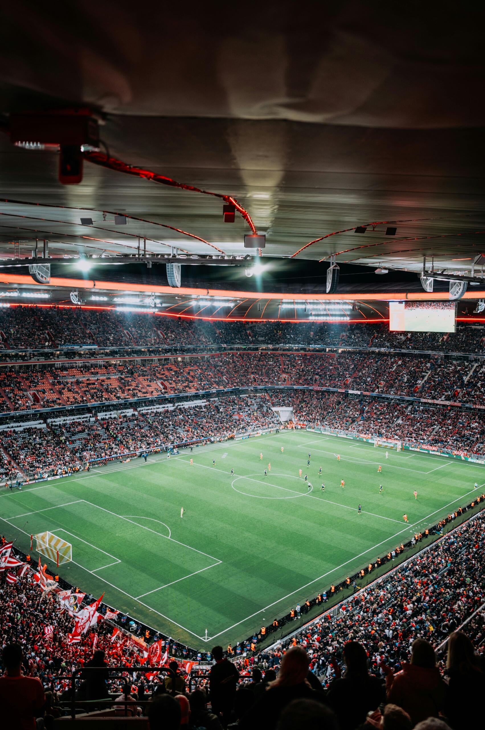 Een voetbalwedstrijd wordt gespeeld in een vol stadion bij nacht.