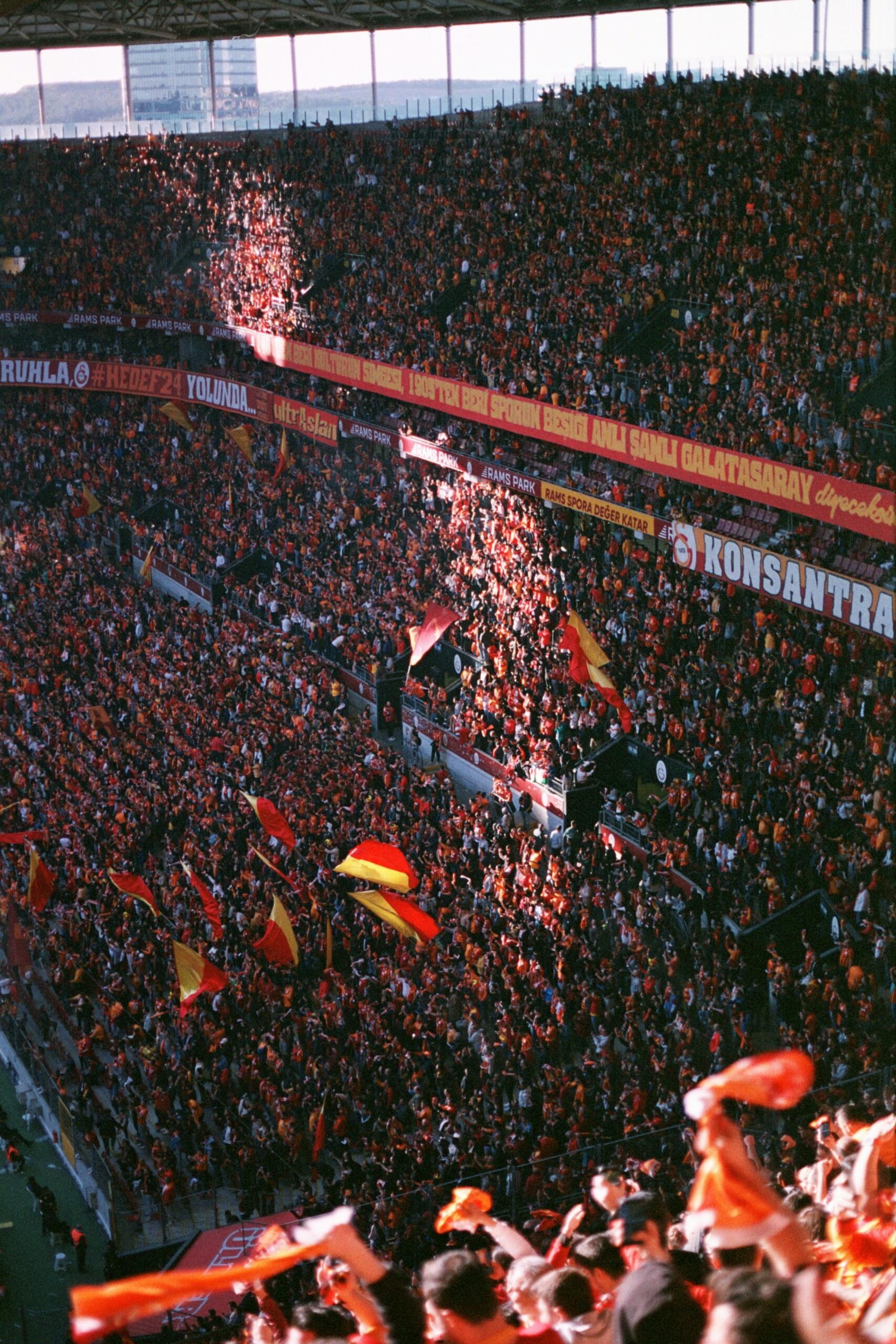 Een groot publiek vult de tribunes van een voetbalstadion tijdens een wedstrijd.