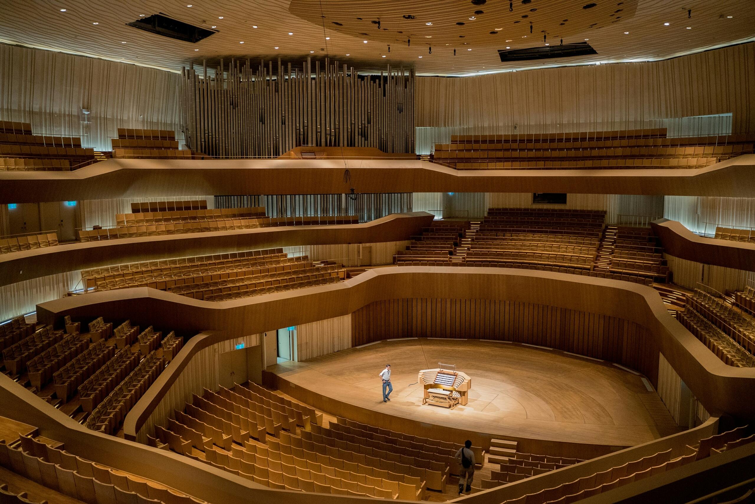 Een grote concertzaal met rijen stoelen en een podium voor muzikale uitvoeringen.