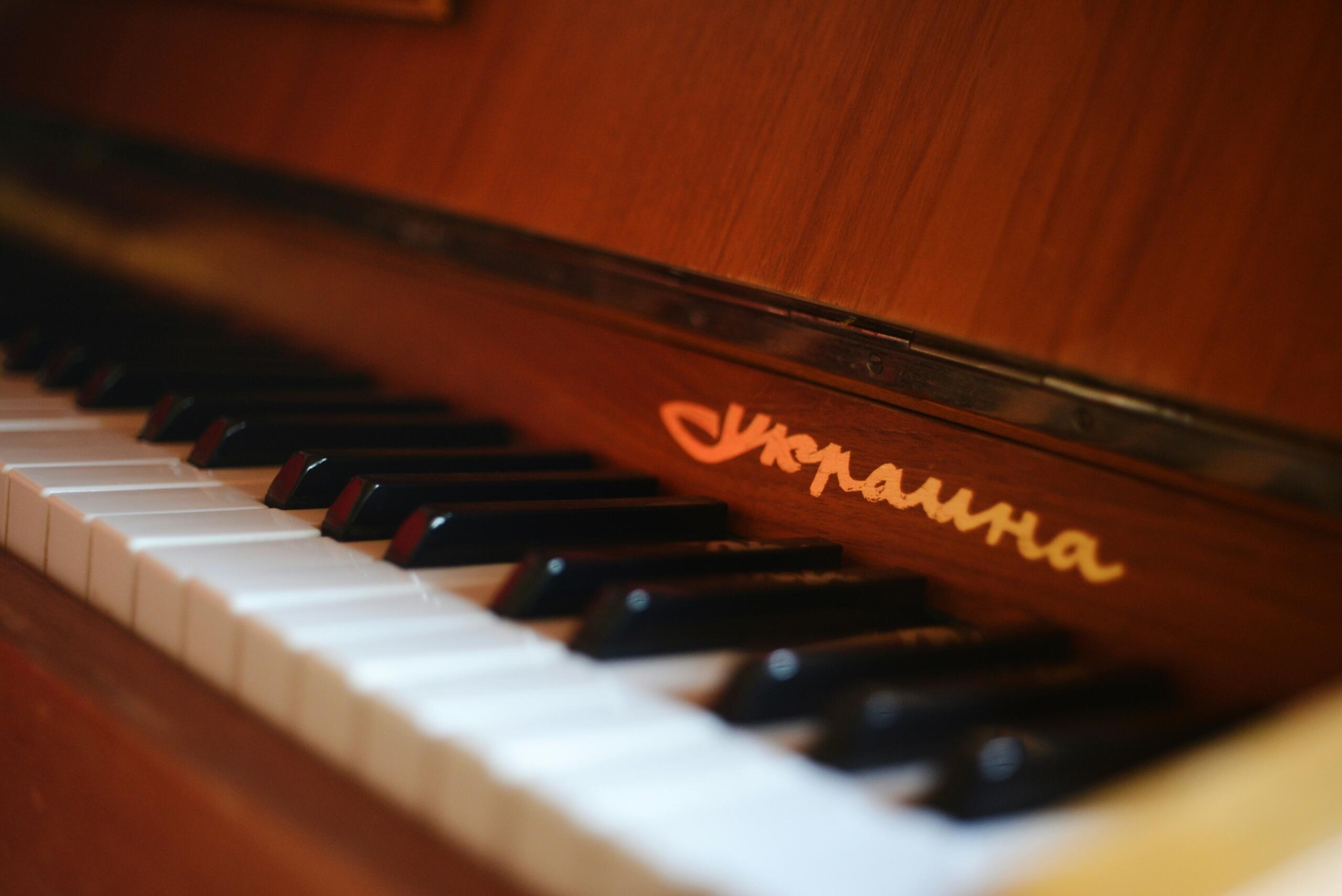 Close-up van de toetsen en merknaam op een piano in een warme houten afwerking.