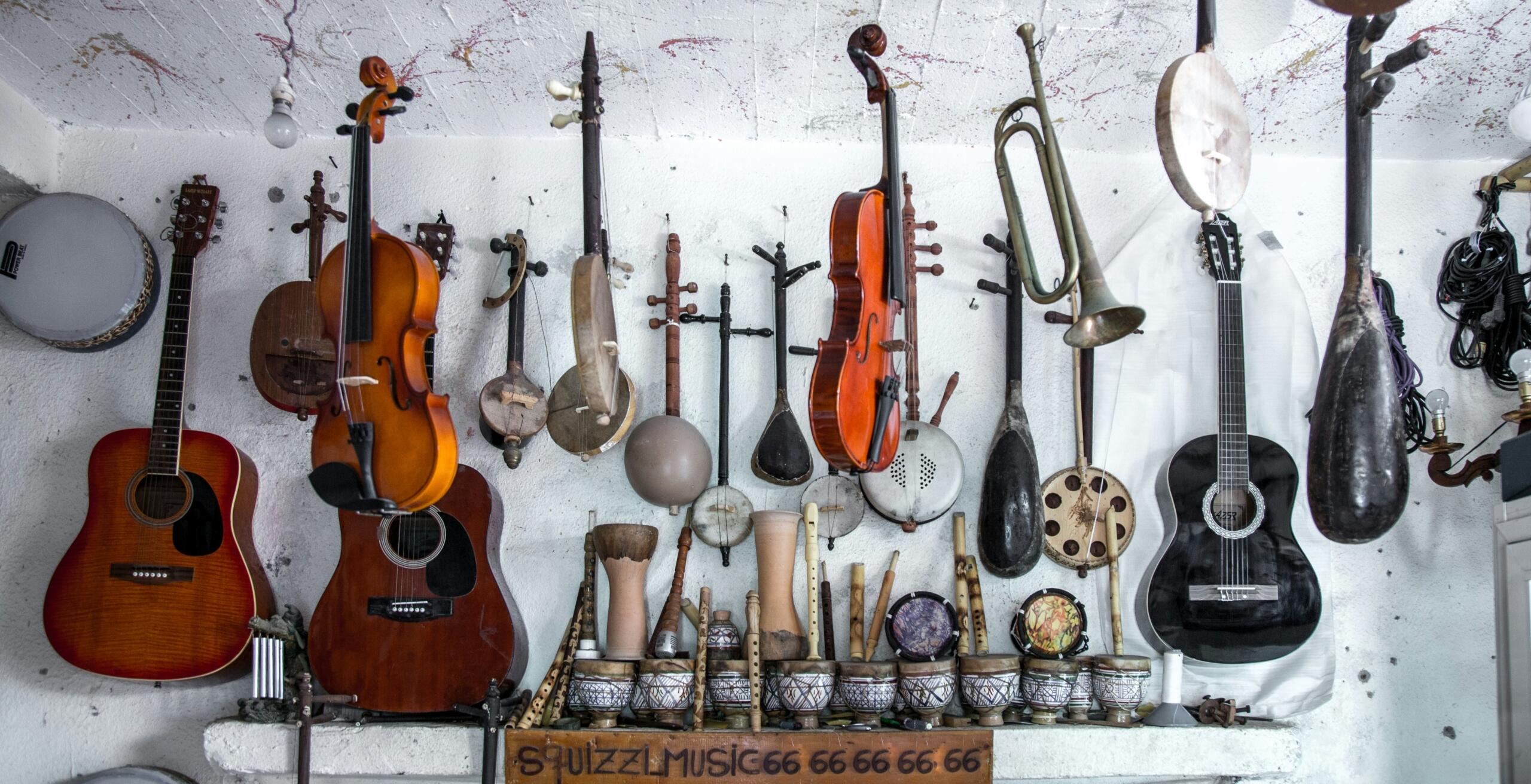 Verschillende muziekinstrumenten hangend aan een muur | Bron: Karim Manjra, via Unsplash