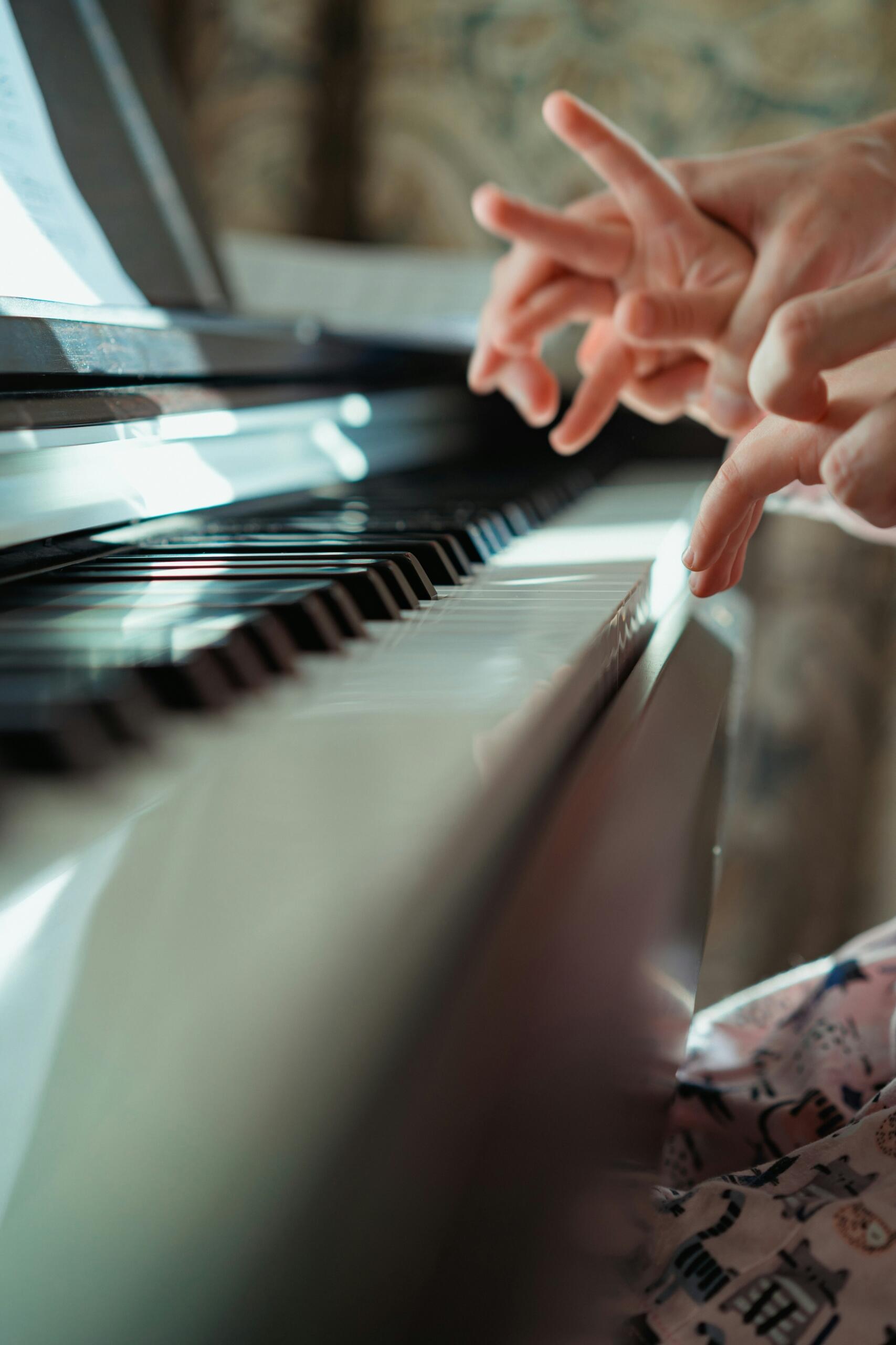 Een leerling krijgt pianoles terwijl een hand de toetsen aanwijst.