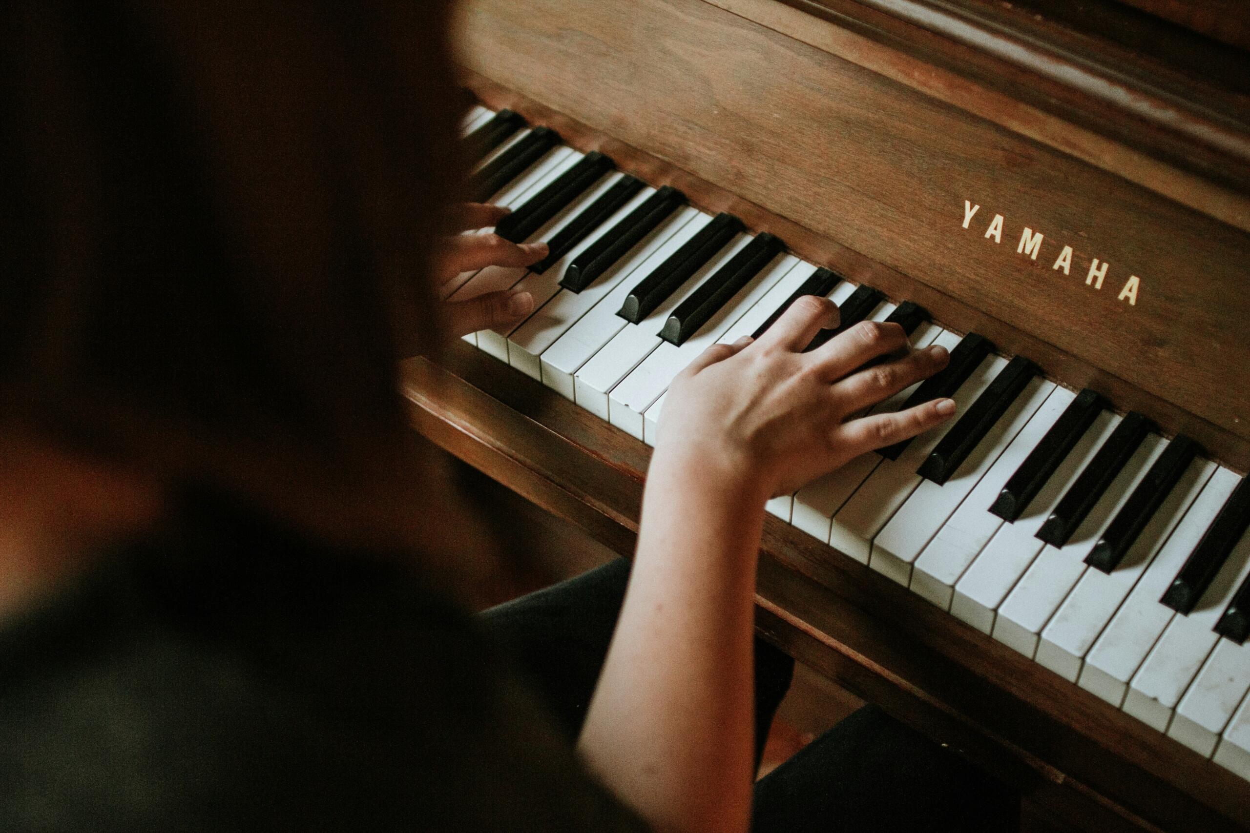 Handen spelen op de toetsen van een houten Yamaha piano Bron: Jordan Whitfield, via Unsplash