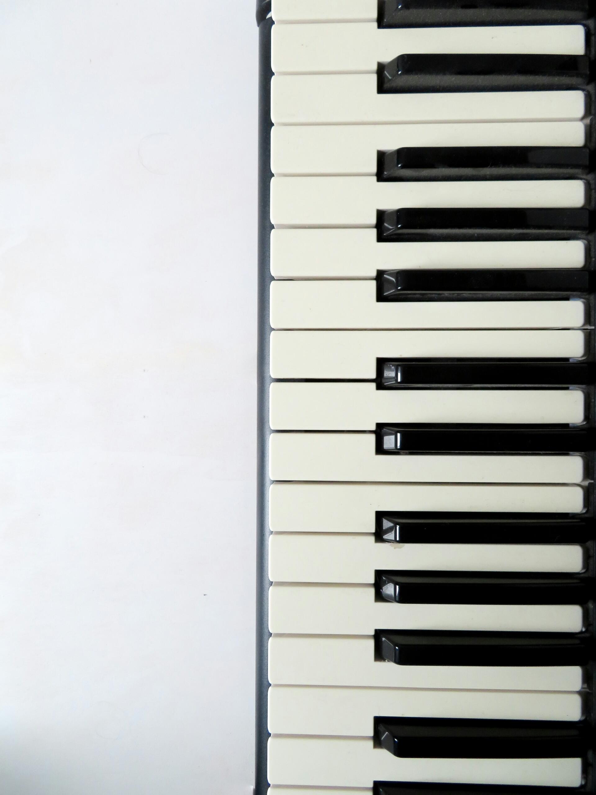 Een close-up van witte en zwarte pianotoetsen tegen een lichte achtergrond.