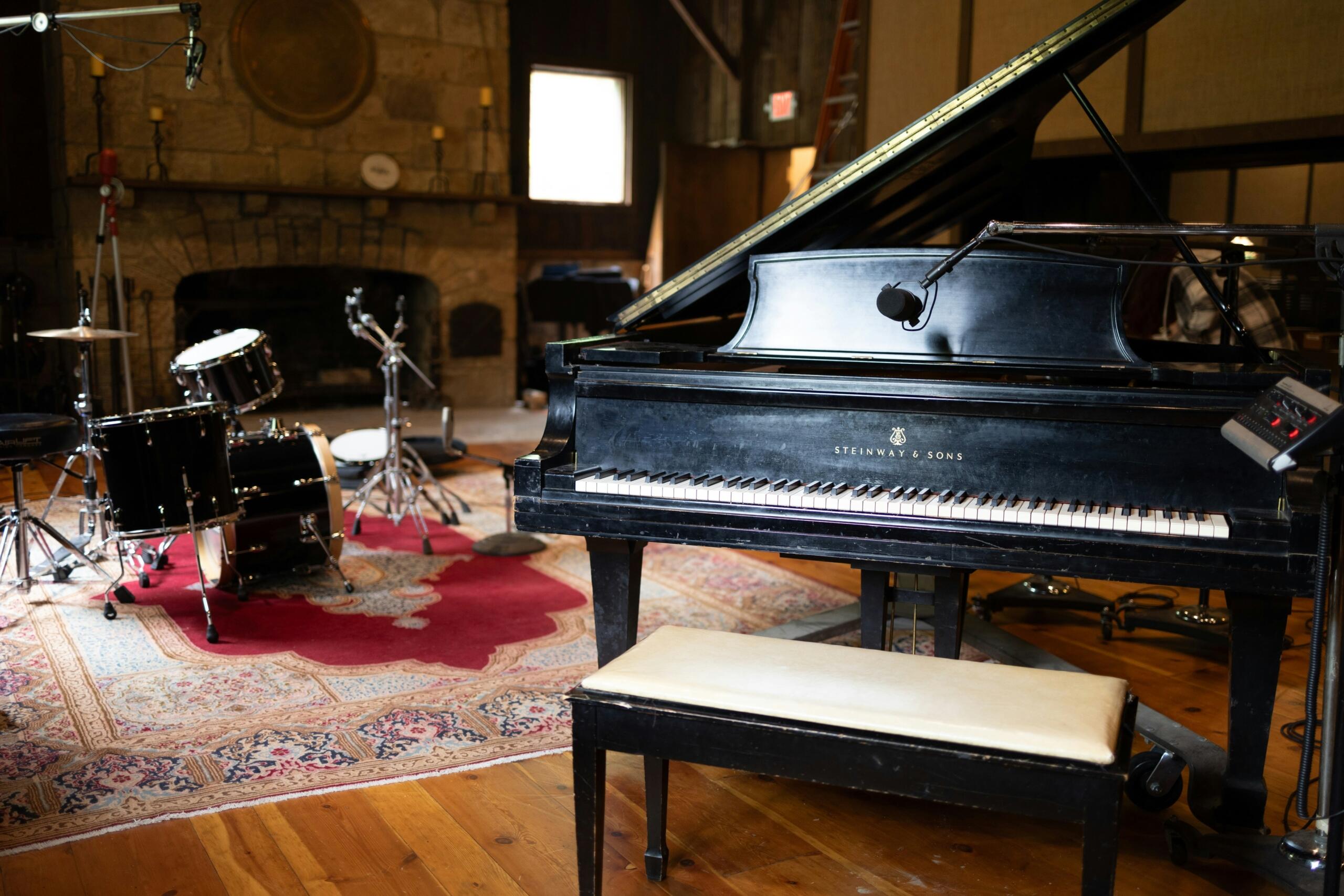 Een Steinway & Sons-piano naast een drumstel in een sfeervolle opnamestudio.