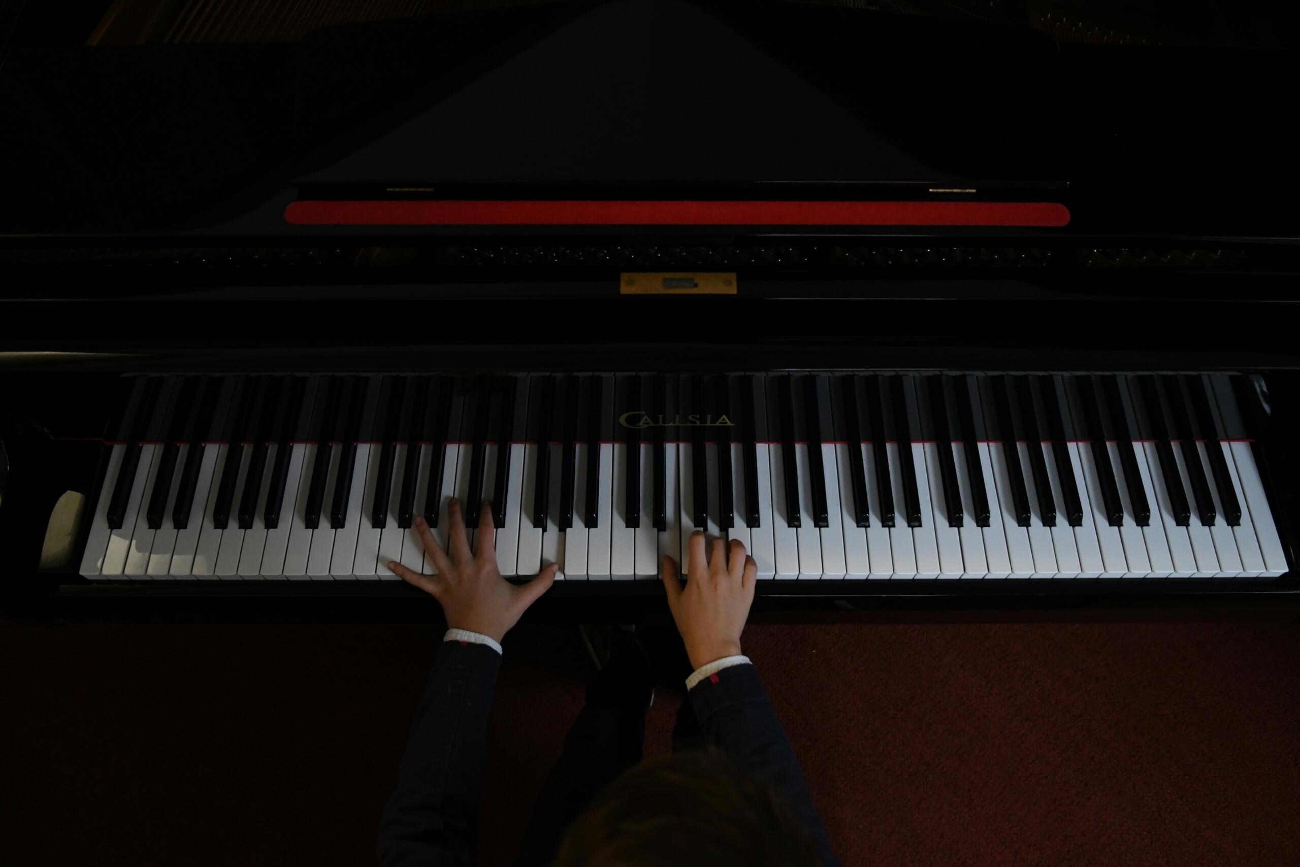 Close-up van handen die pianotoetsen bespelen tijdens het oefenen.