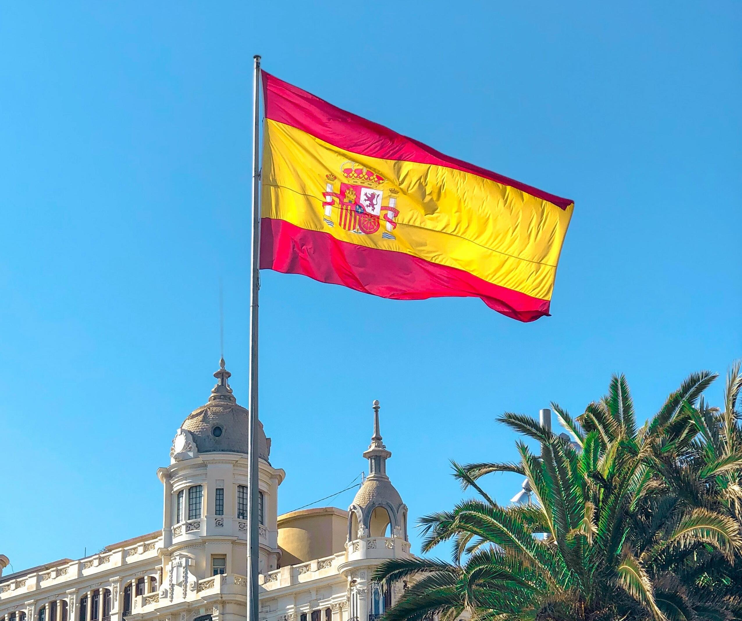 De Spaanse vlag wappert in Alicante, met Casa Carbonell op de achtergrond | Bron: Arthur Gomes Pont, Unsplash