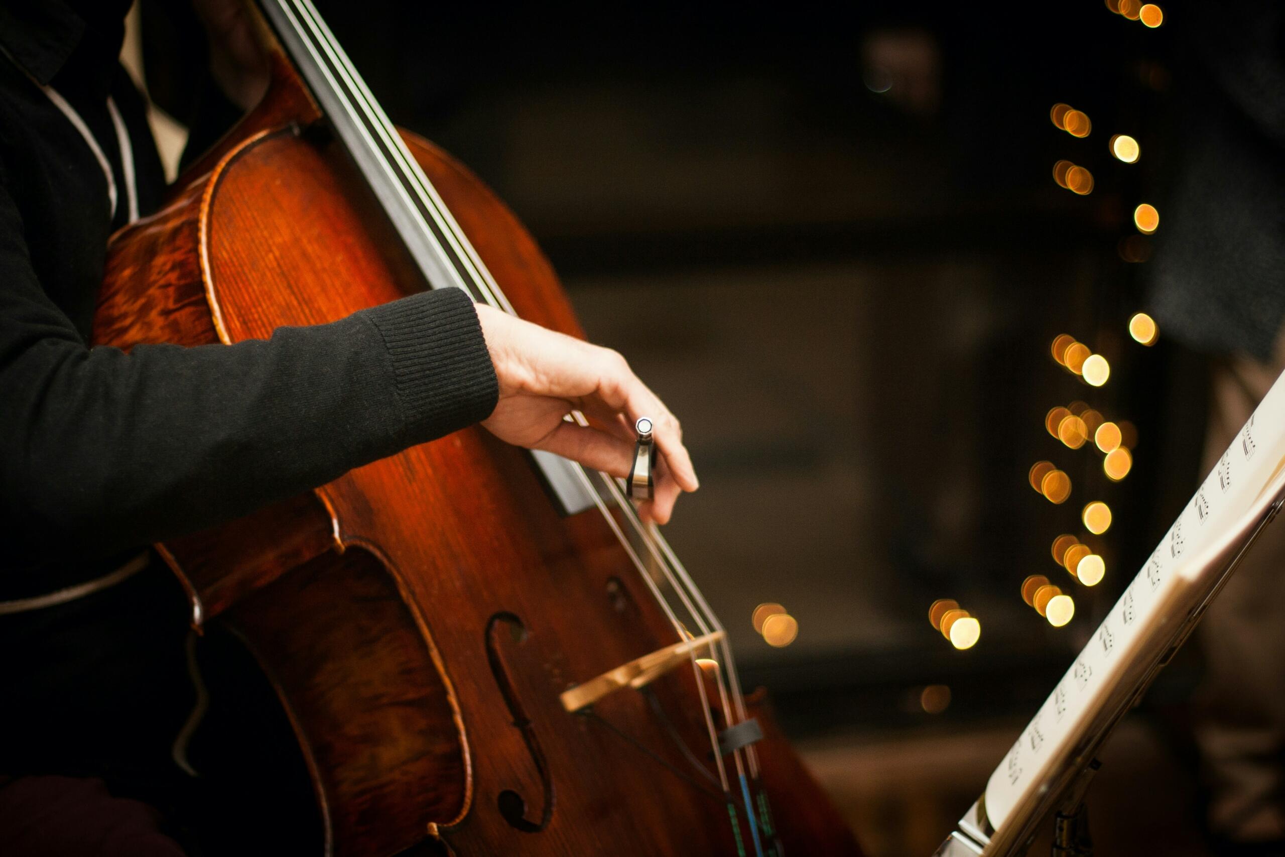 Cellist speelt cello naast bladmuziek in een warme muzikale setting | Manny Becerra, via Unsplash