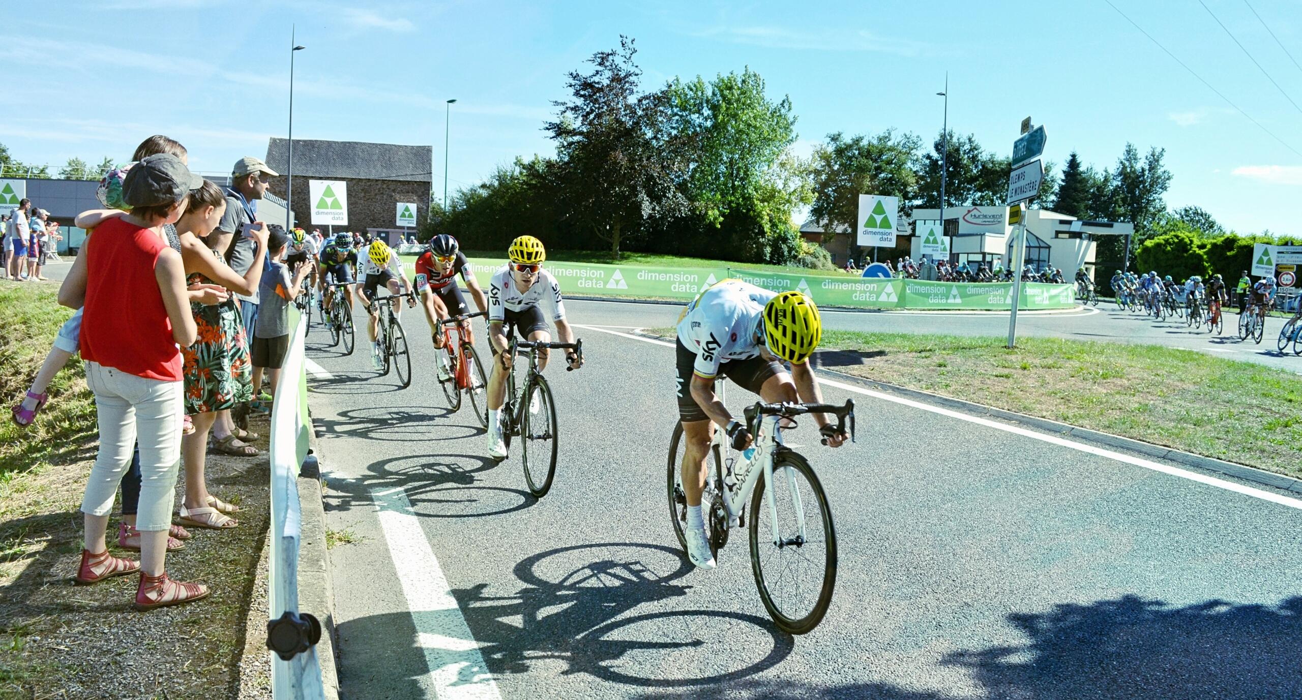 Meerdere wielrenners rijden in wedstrijdtempo over een weg.
