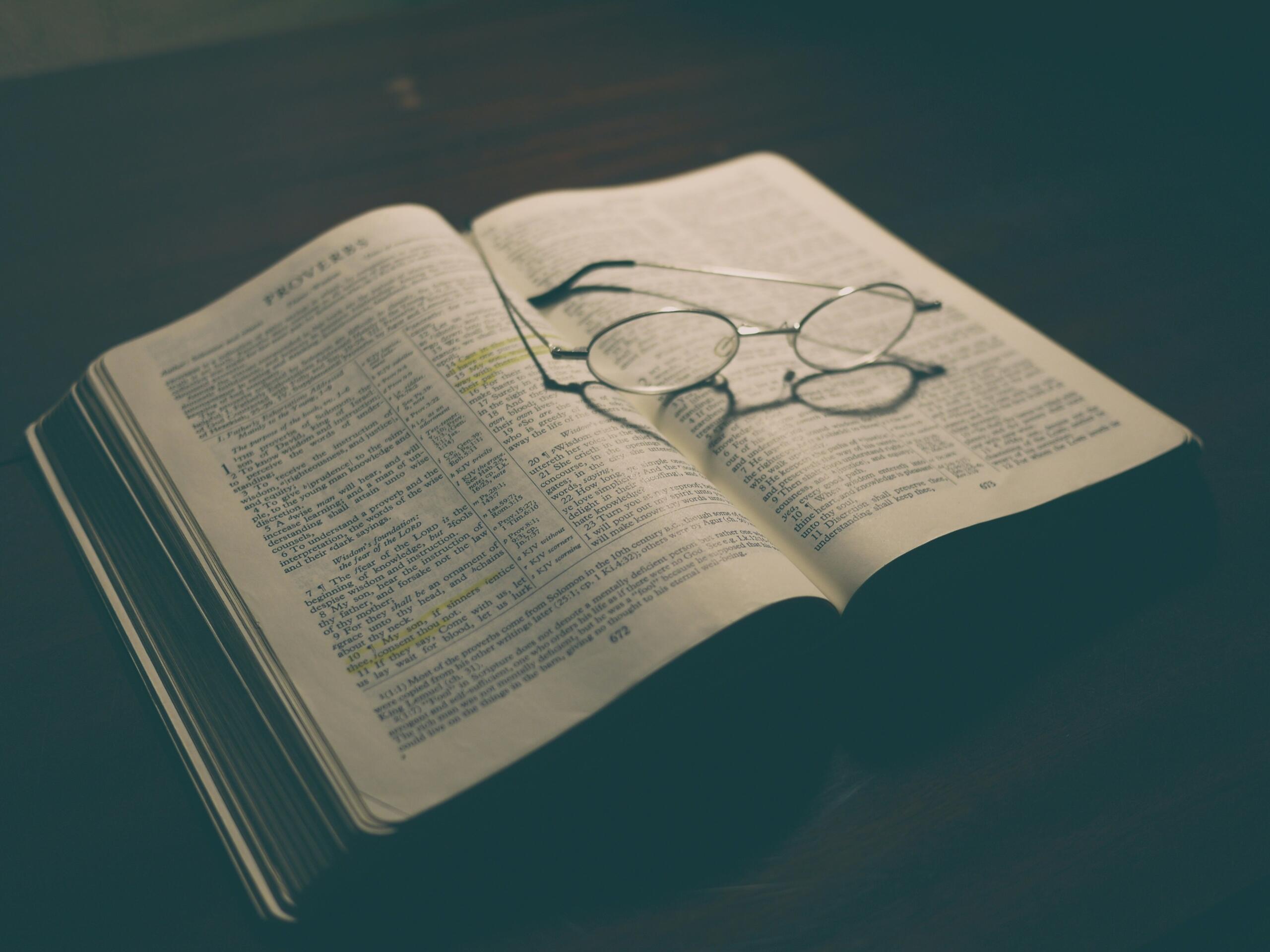 Open boek met een bril erop als beeld bij poëzie en songteksten | Bron: Aaron Burden, via Unsplash