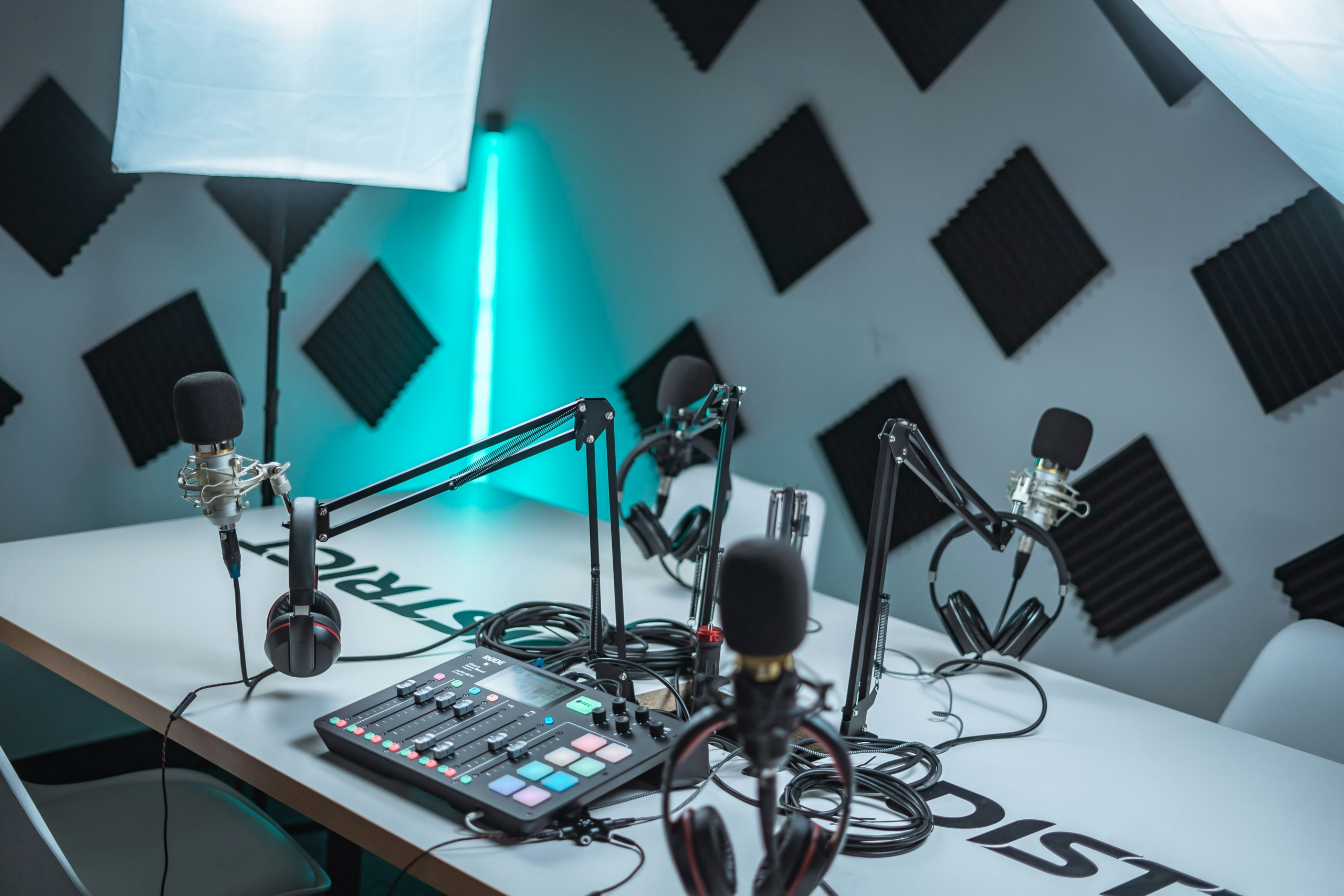 Een tafel met meerdere microfoons, koptelefoons, kabels en audioapparatuur in een studio.