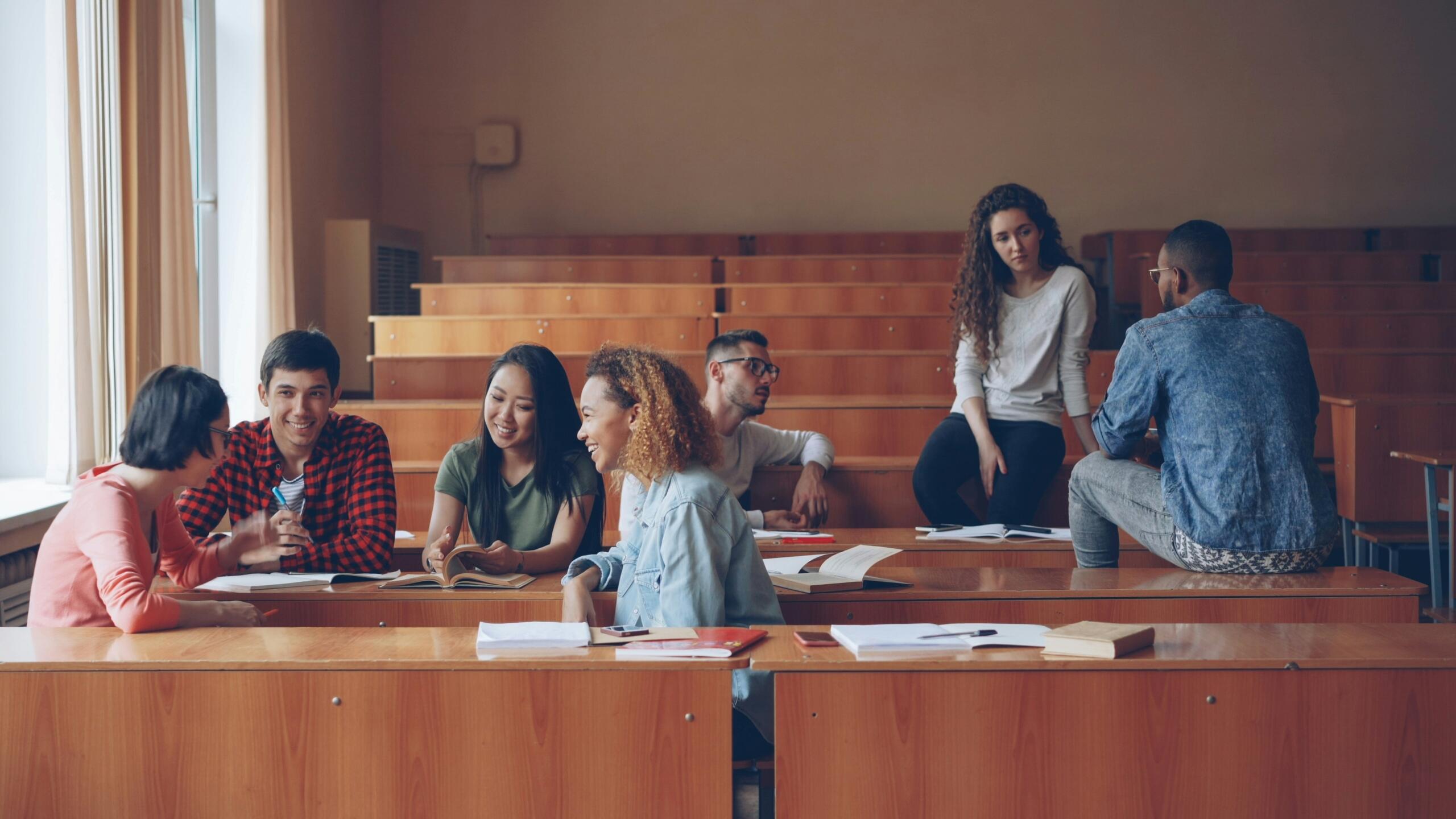 Studenten zitten in een collegezaal en praten met elkaar.