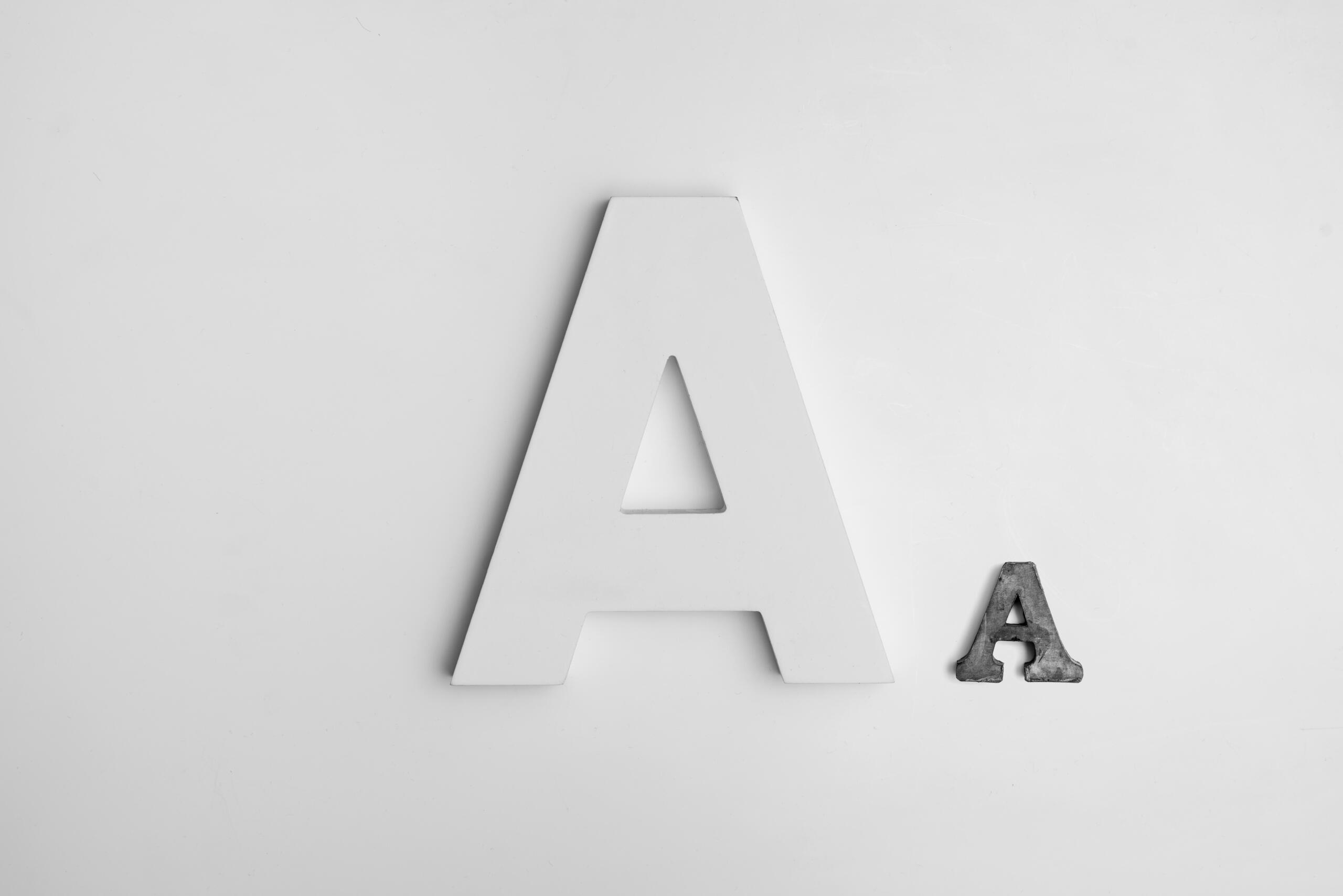 Een grote witte hoofdletter A en een kleinere donkere hoofdletter A liggen op een witte ondergrond.