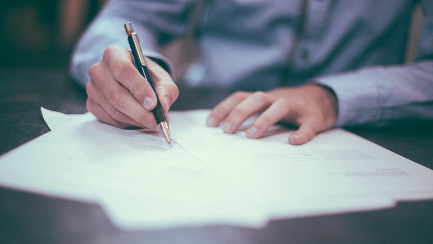 Een persoon ondertekent een document met een pen.