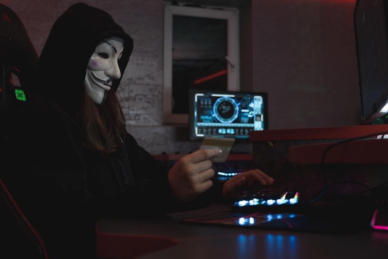 Gemaskerde computergebruiker in een donkere ruimte