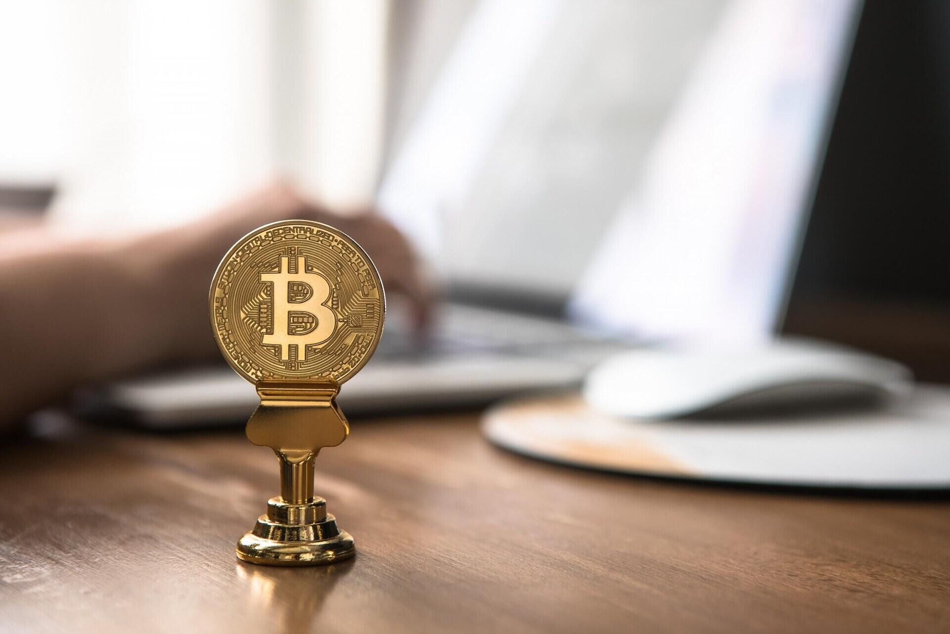 Bitcoinmunt op een standaard naast een computer