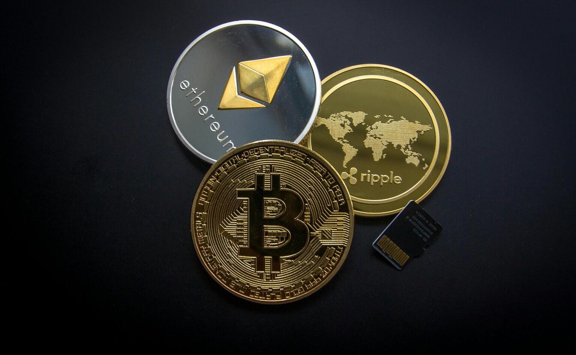 Munten met symbolen van bitcoin, ether en ripple op een donkere achtergrond