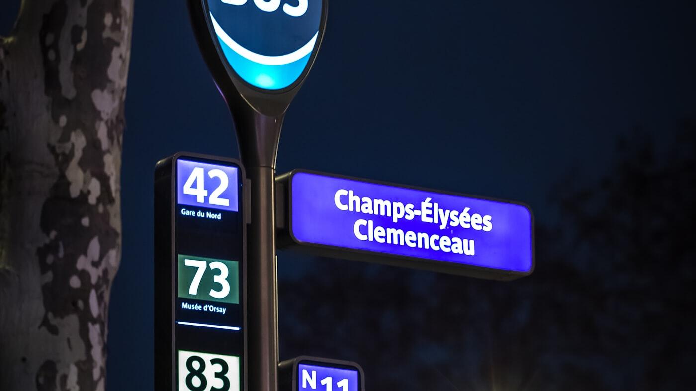 Verlichte halteborden van Parijse buslijnen staan tegen een donkere achtergrond.