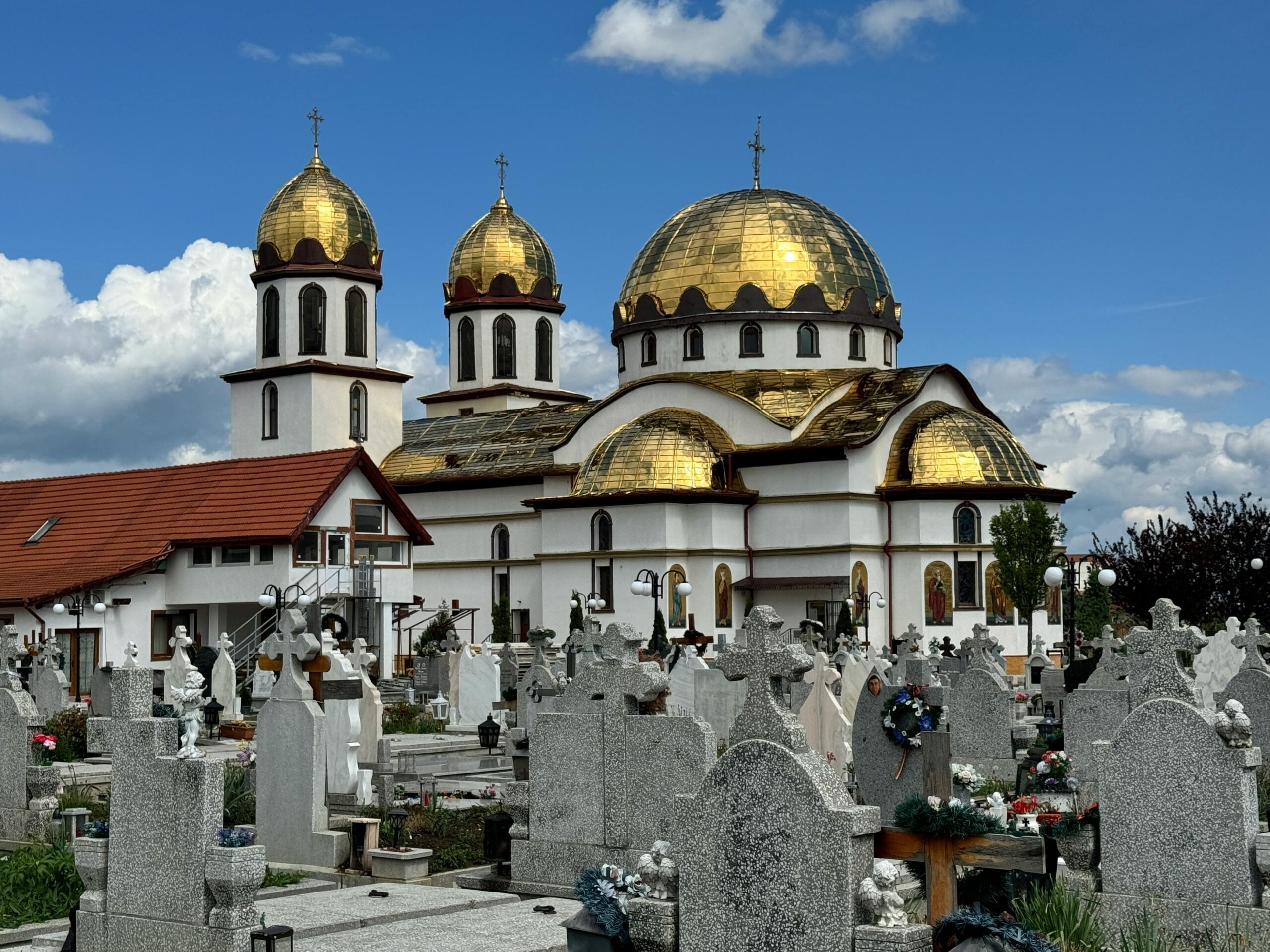 Grafstenen op een begraafplaats met een kerk in Roemenië
