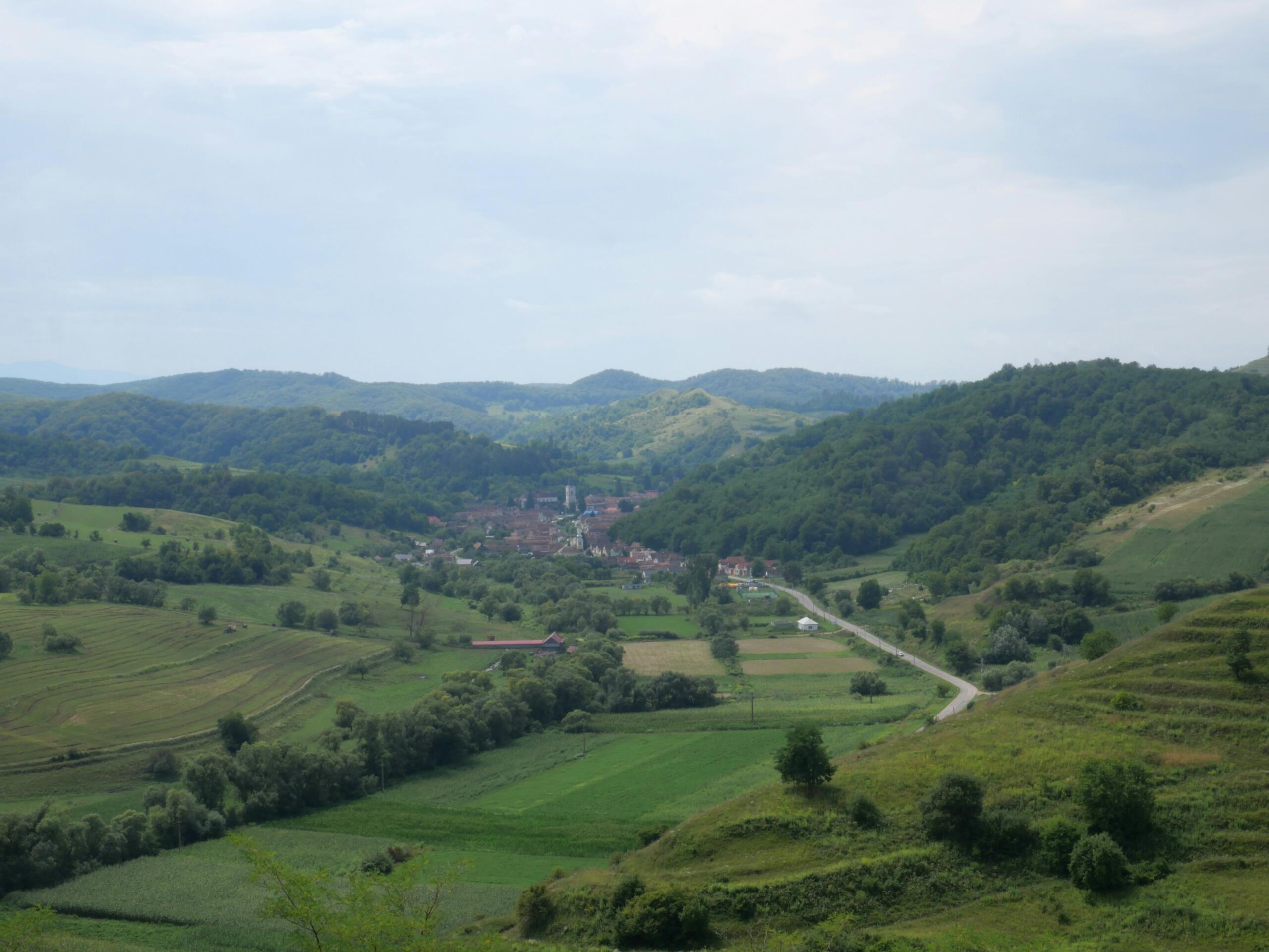 Dorp tussen groene heuvels en velden in Transsylvanië