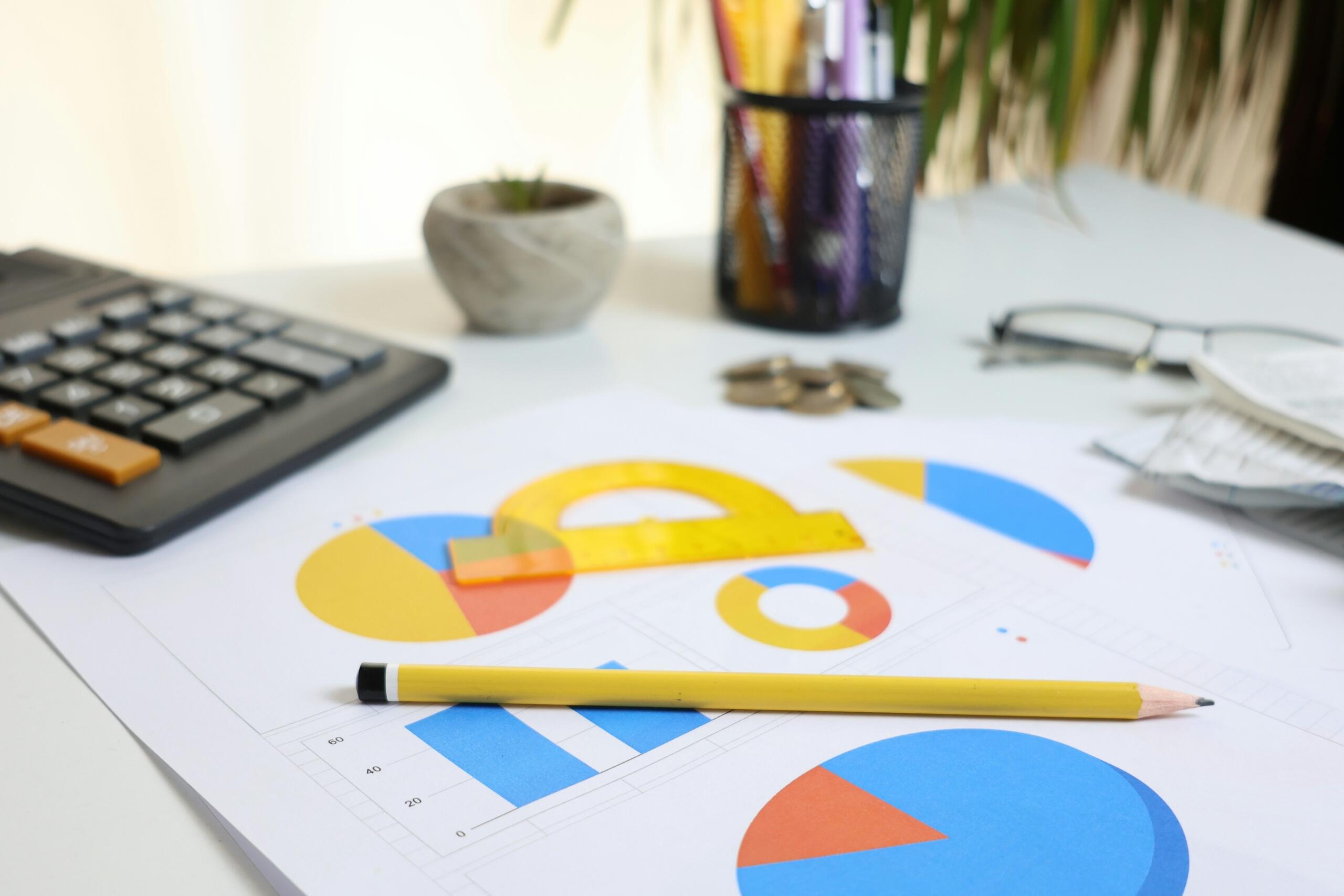 Calculator naast grafieken en een potlood op een bureau