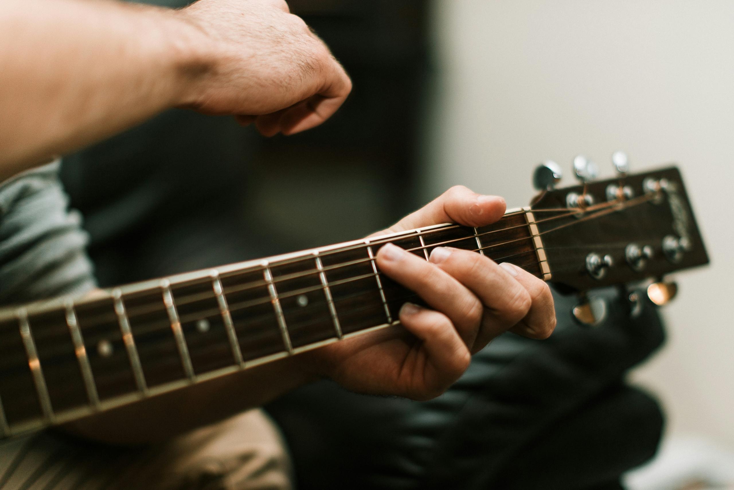 Nærbilde av hender som spiller gitar