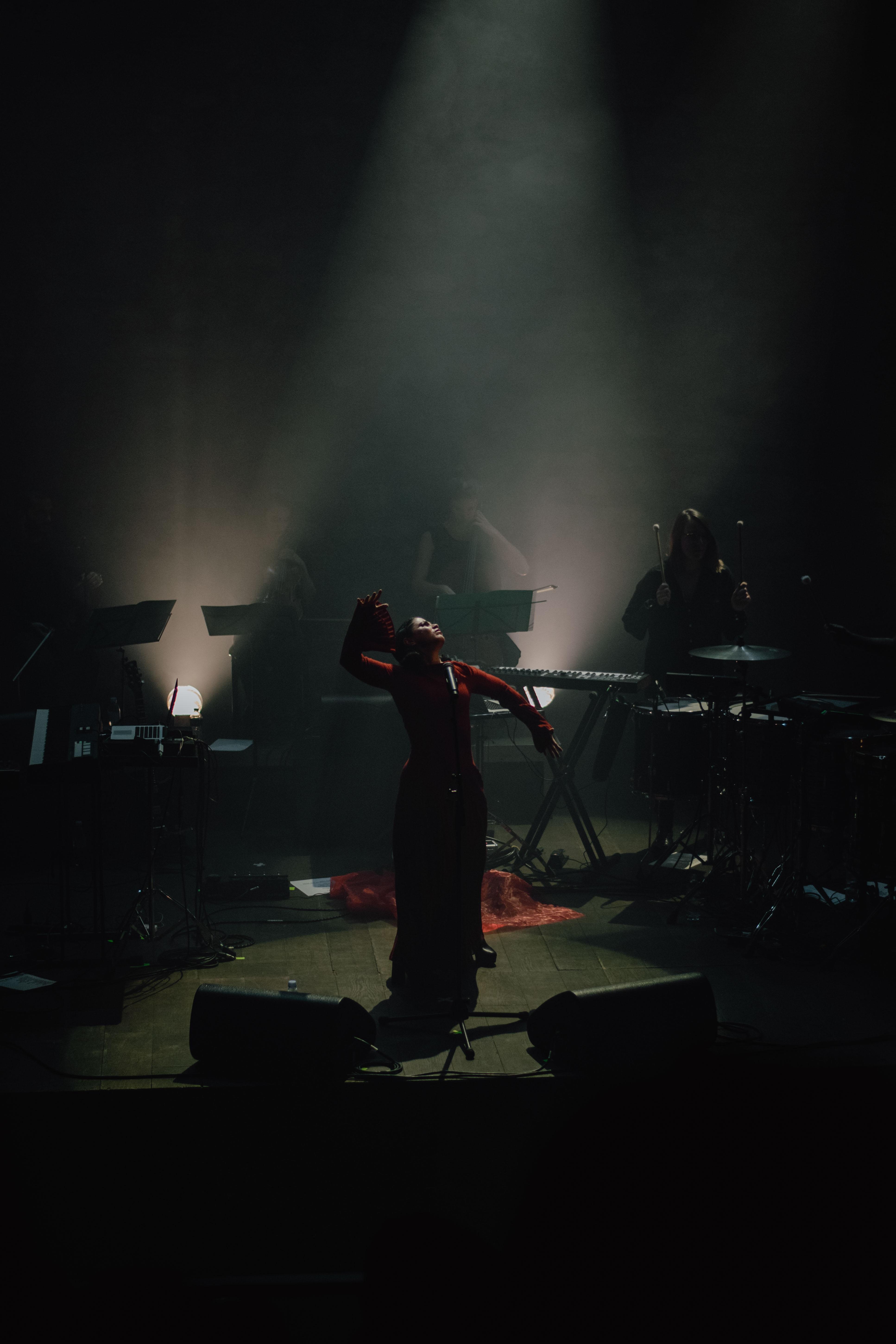 En kvinne synger og danser på en dramatisk belyst scene